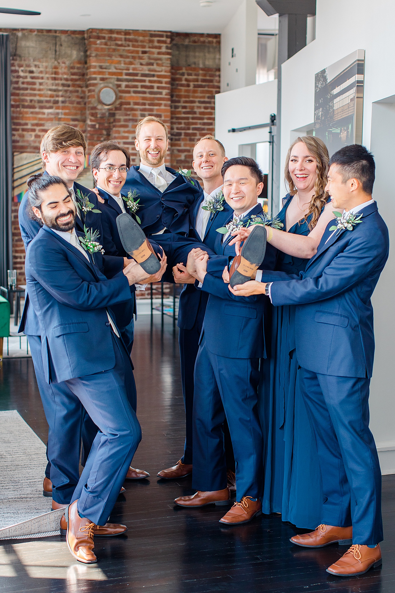 groomsmen lift the groom up in the air