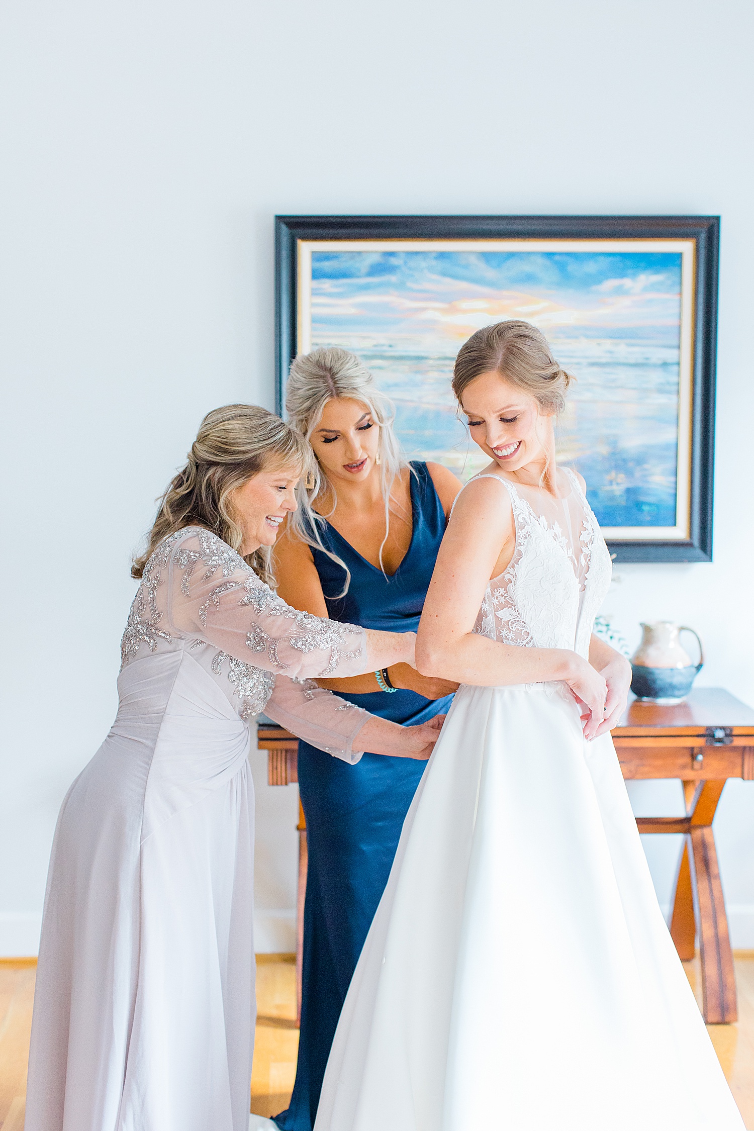bride getting ready with the help of her mom and MOH
