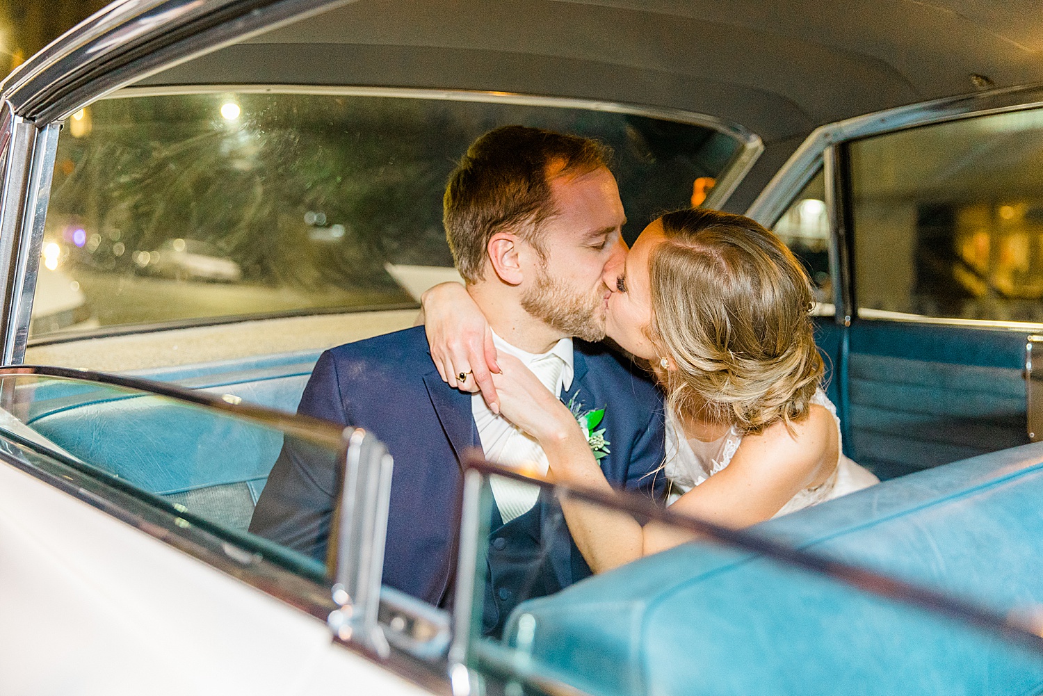 bride and groom kiss in their getaway car