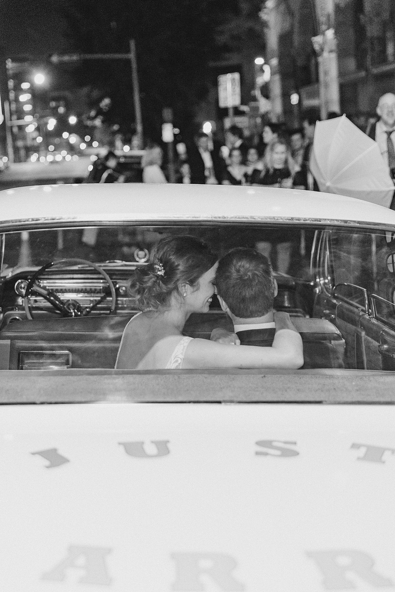 bride and groom in the back of car as it drives away