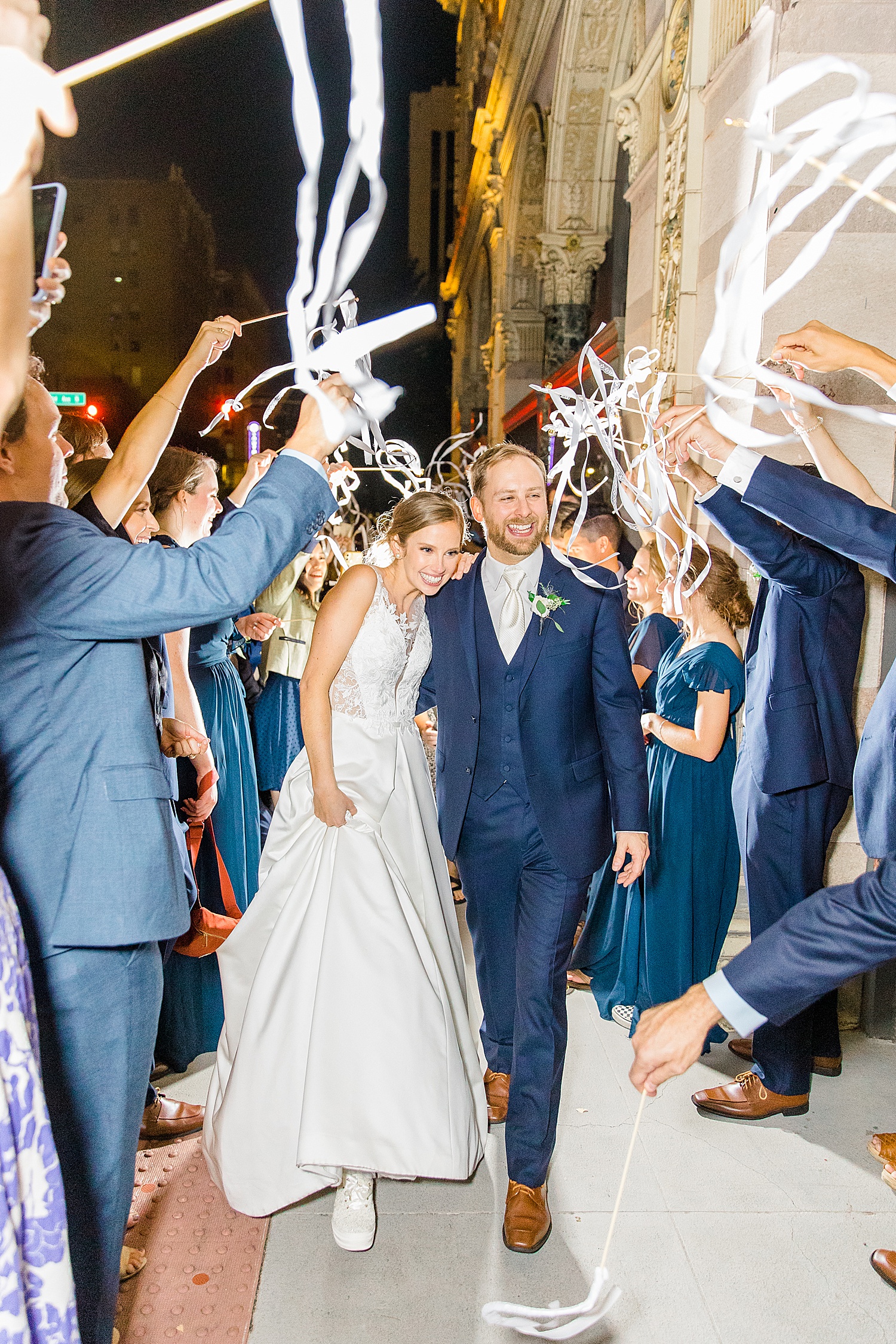 newlyweds at the end of their wedding night as wedding guests wave streamers