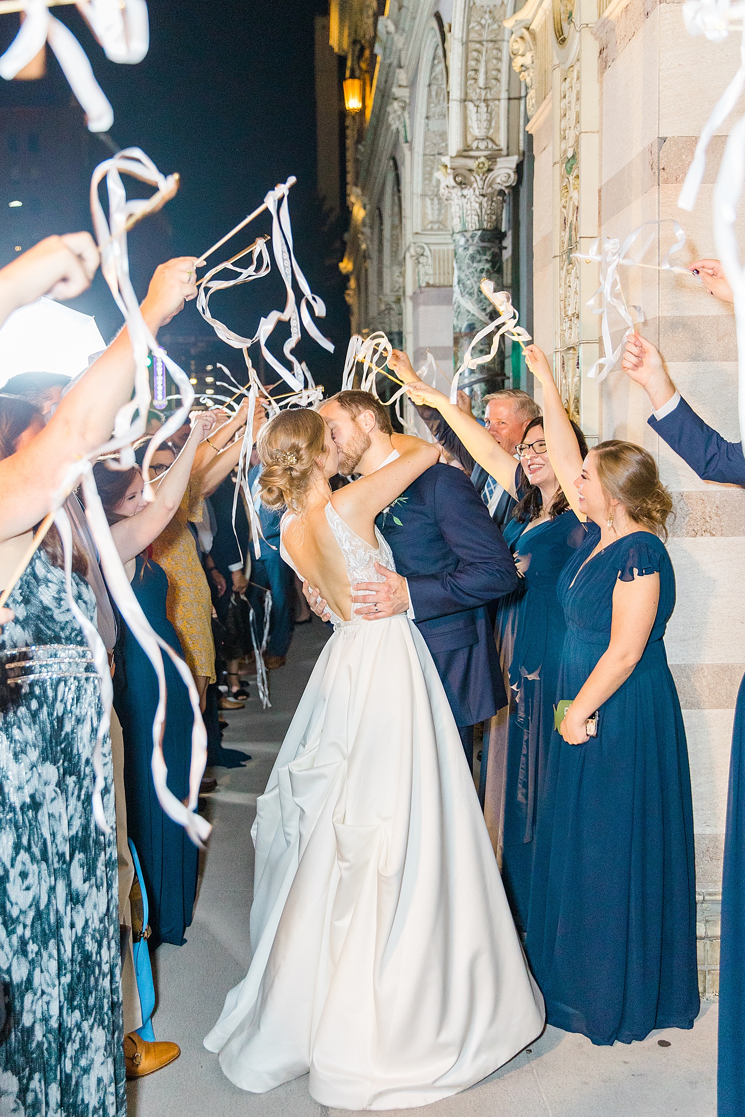 newlyweds kiss as their wedding guests wave streamers