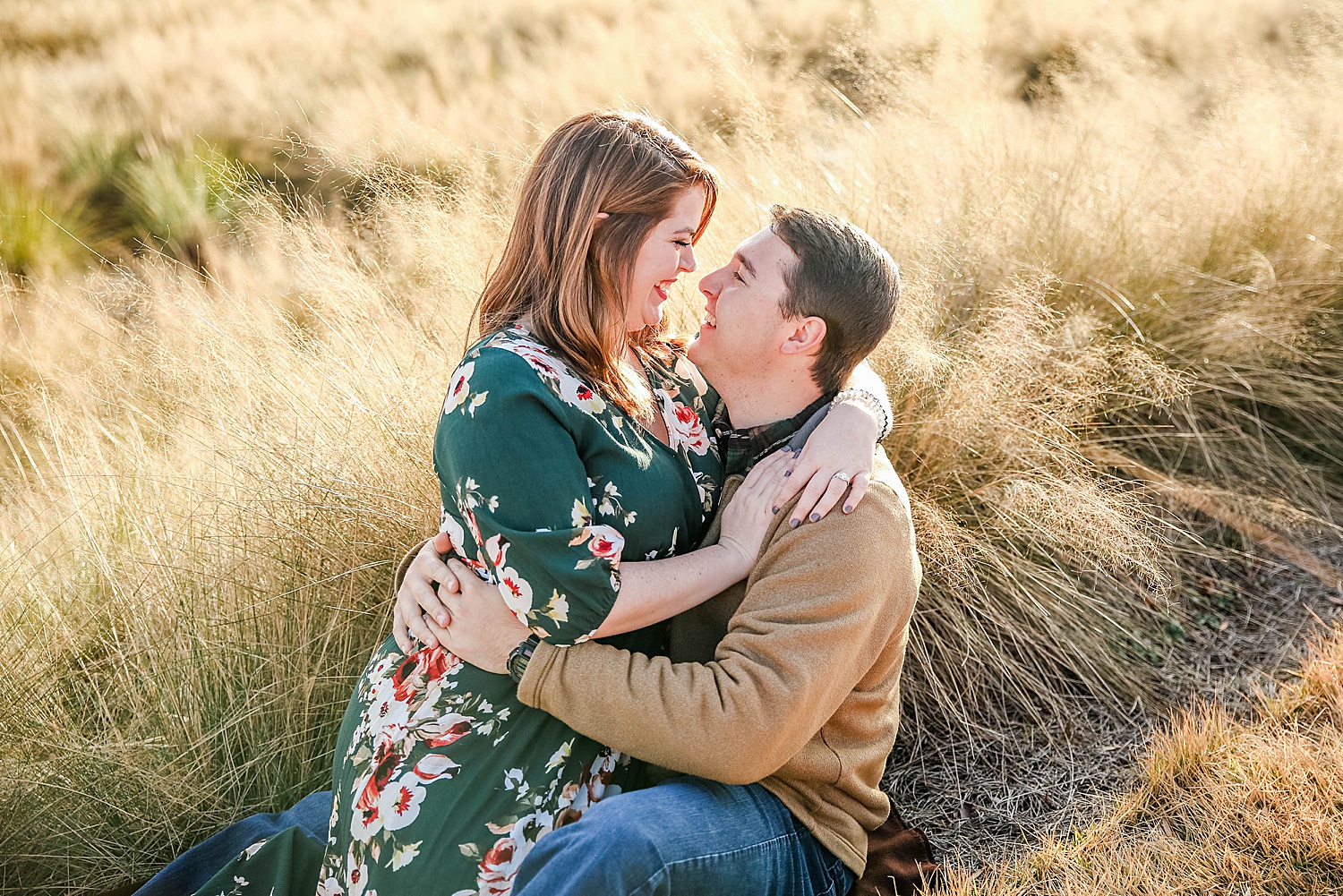 engaged couple snuggle close in the tall grass at Railroad park in Alabama