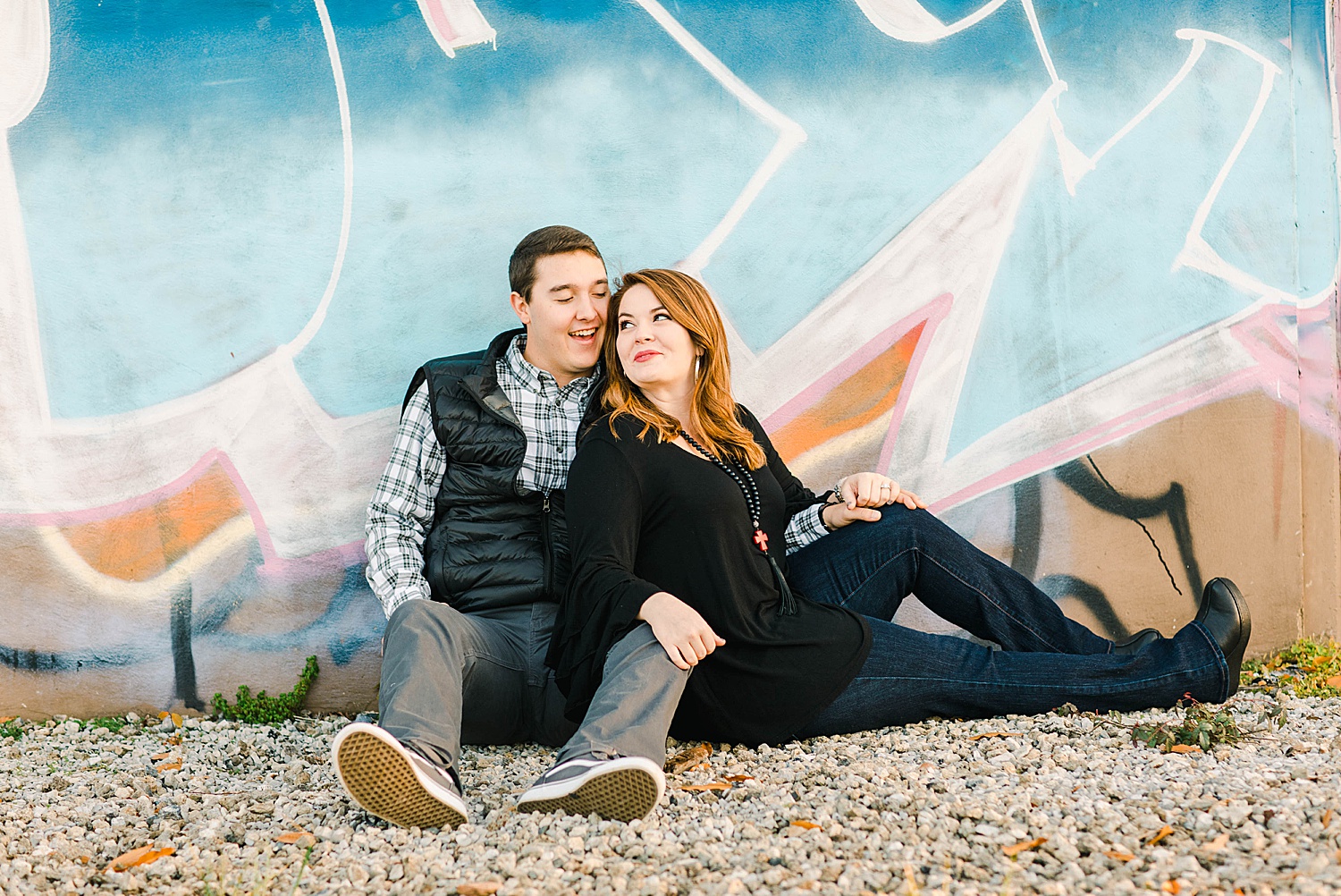 Engaged couple sit against graffiti wall in downtown Birmingham engagement session
