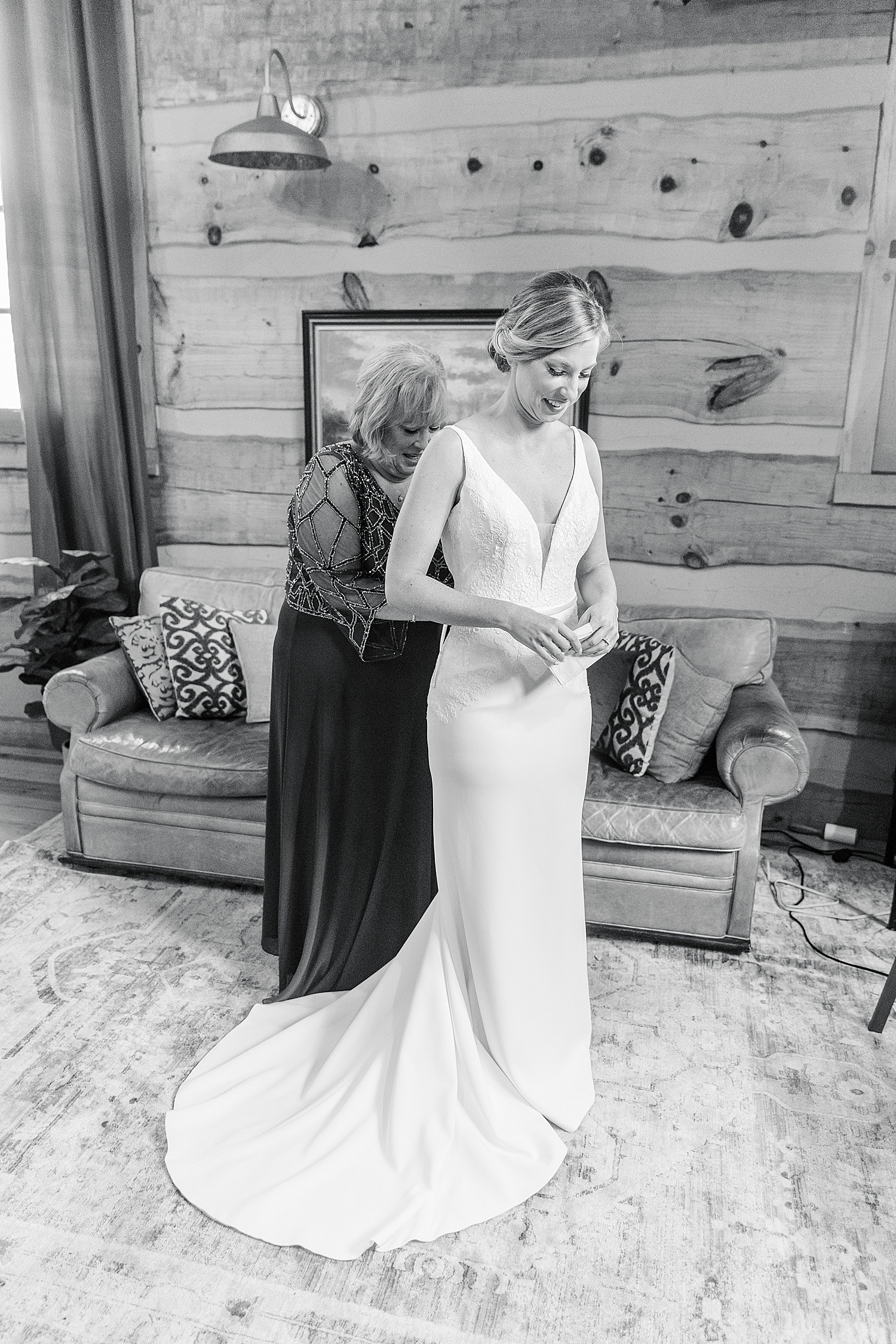 bride and her mom getting wedding dress on