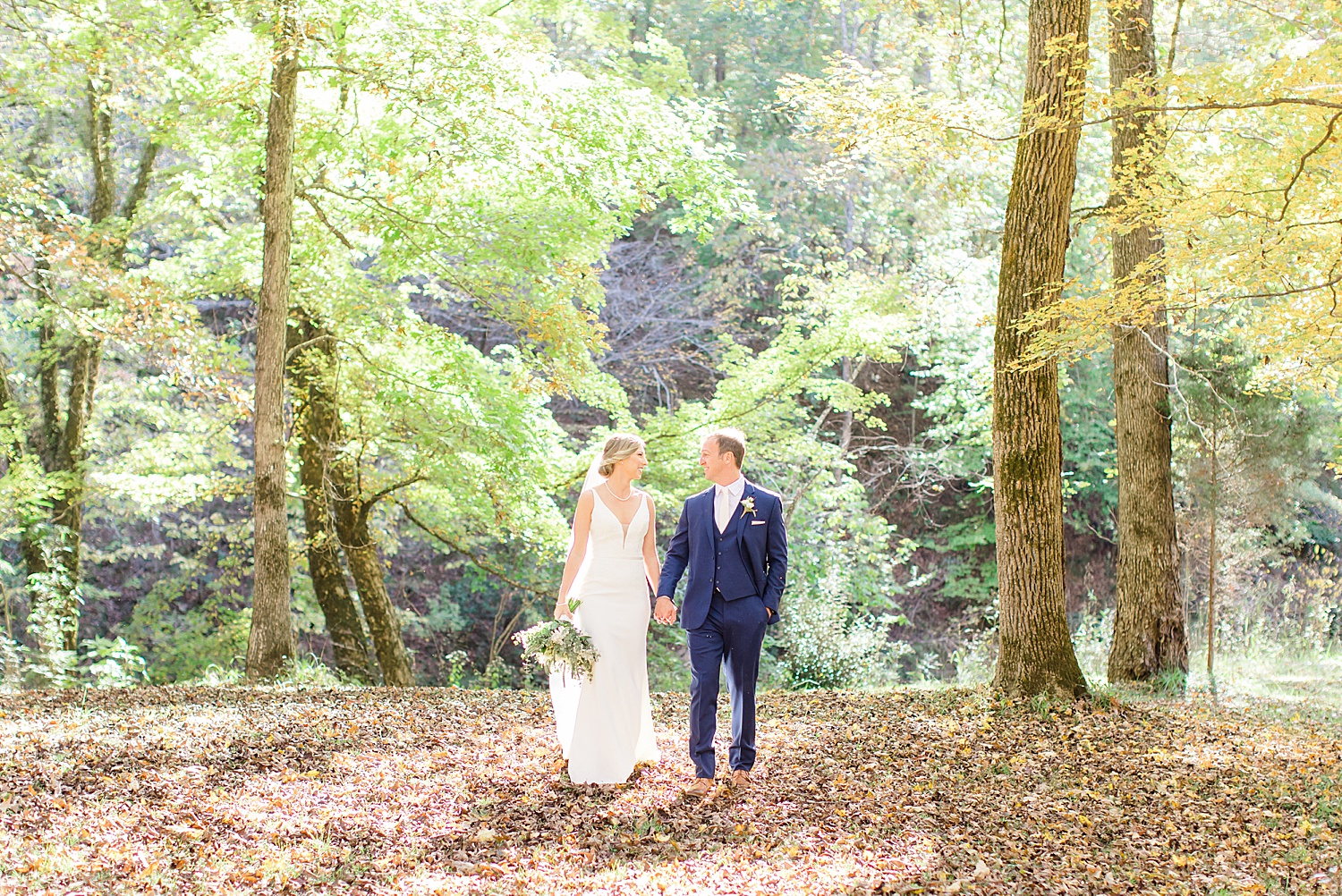 couple walking in the woods at Swann Lake Stables Wedding