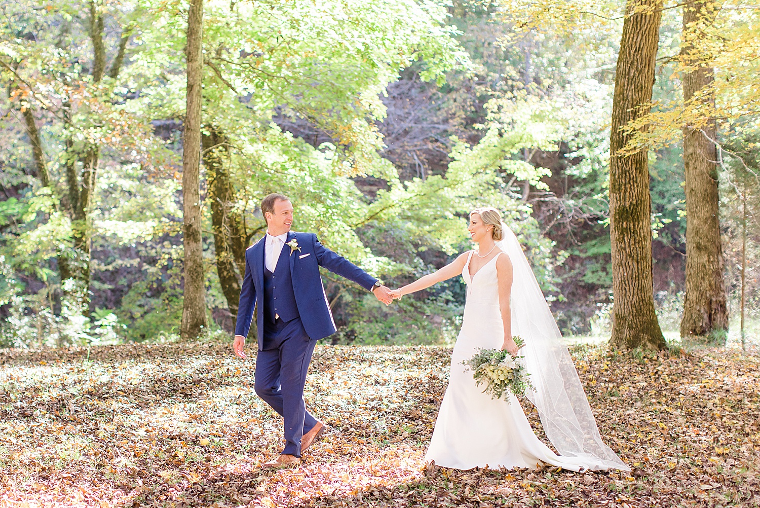 groom leads bride through the woods