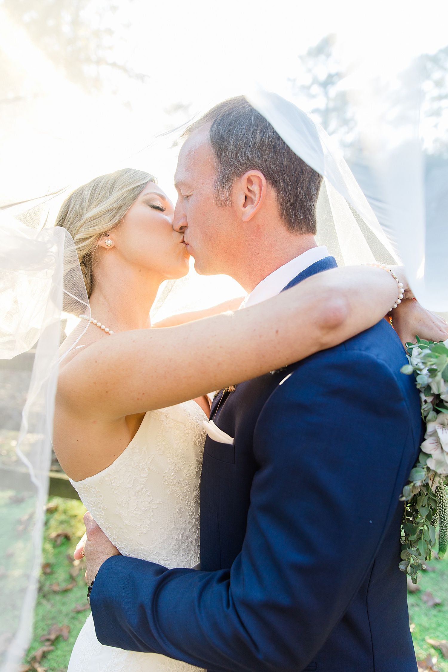 newlyweds kiss with veil wrapped around them