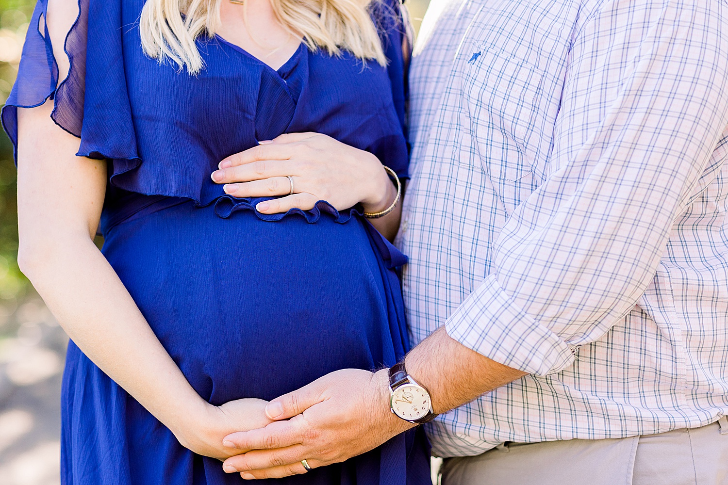 mom and dad wrap arms around mom's belly during maternity session