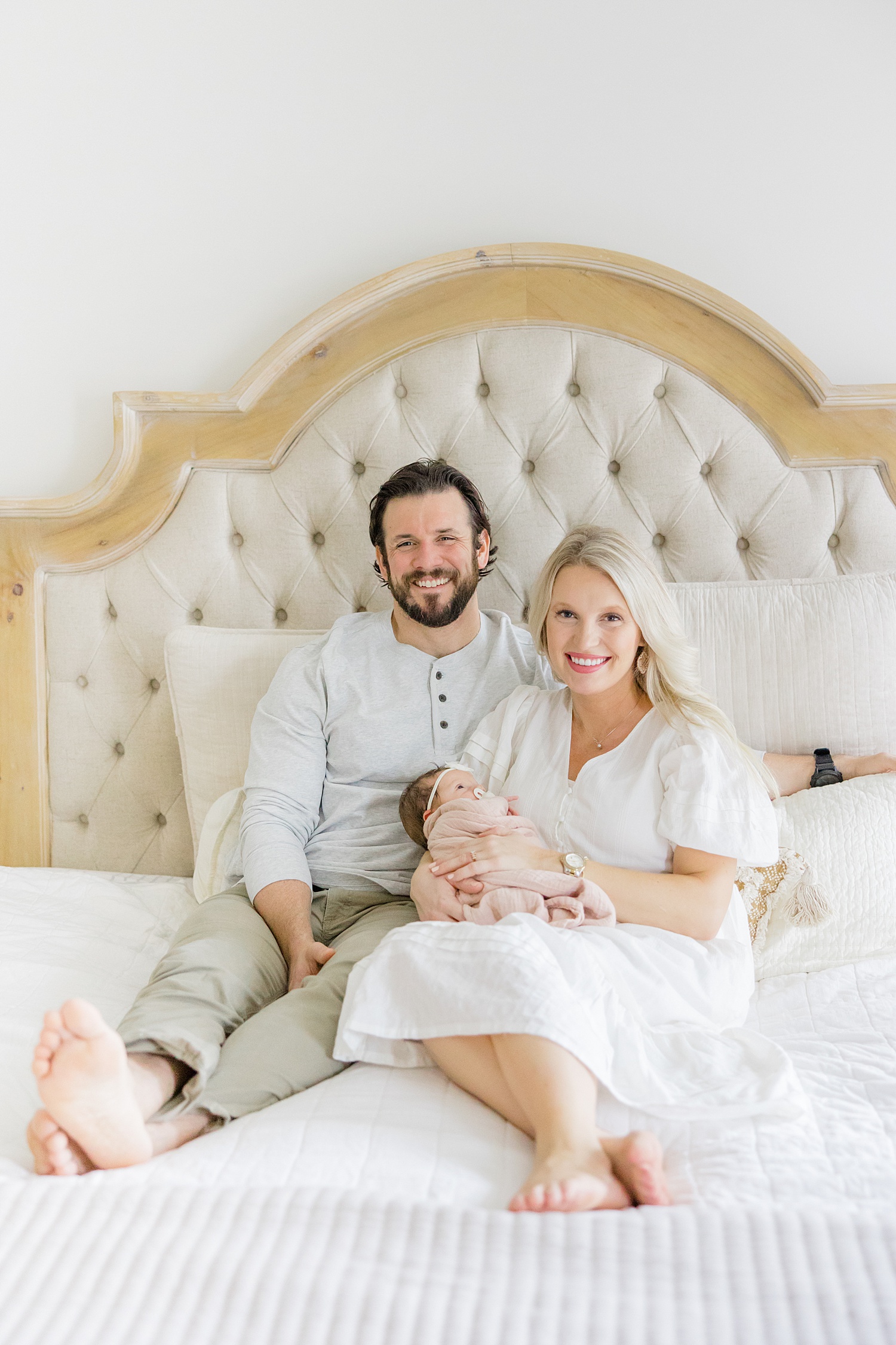 parents sit on bed holding newborn girl