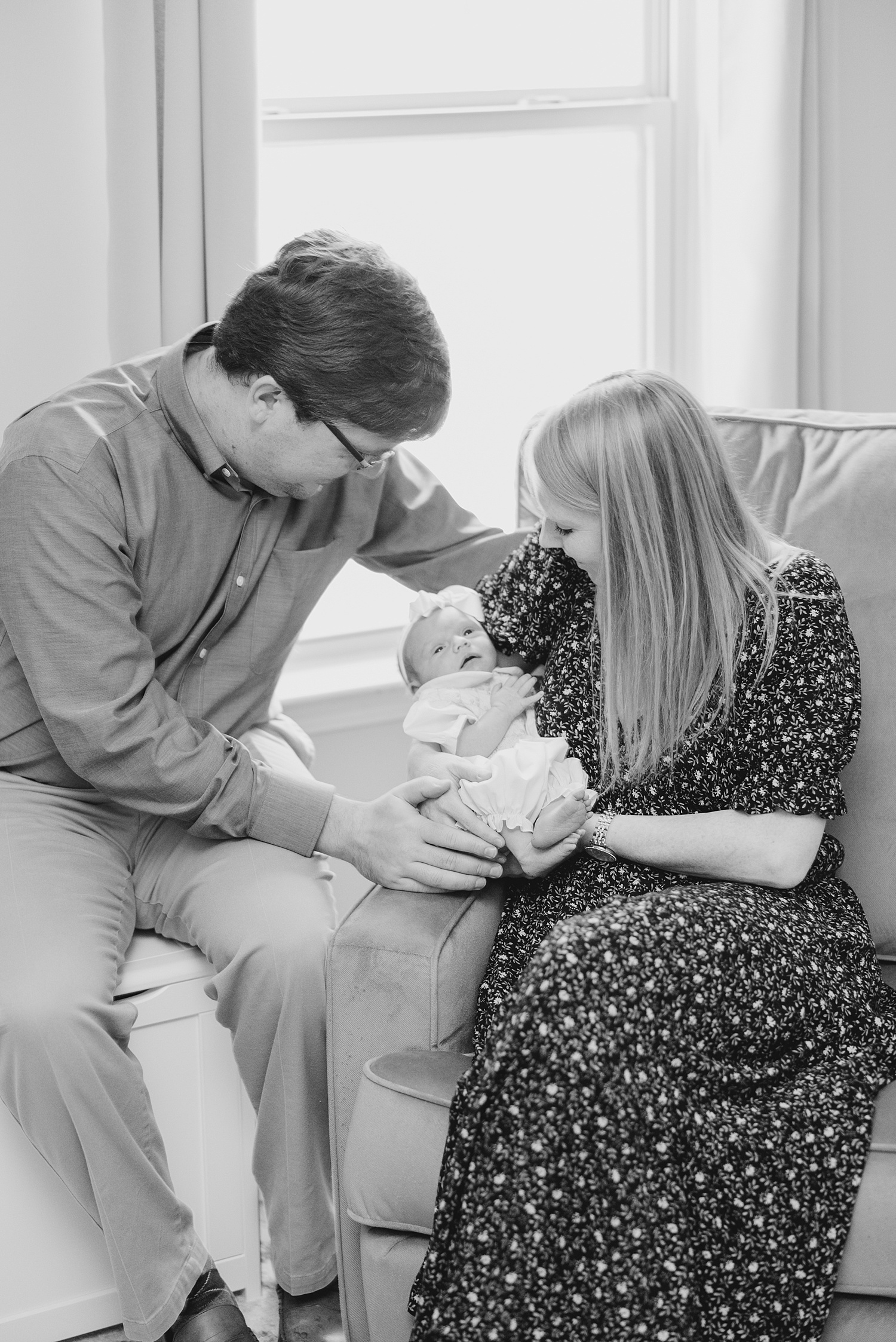 parents look down at newborn daughter during AL In-home newborn session