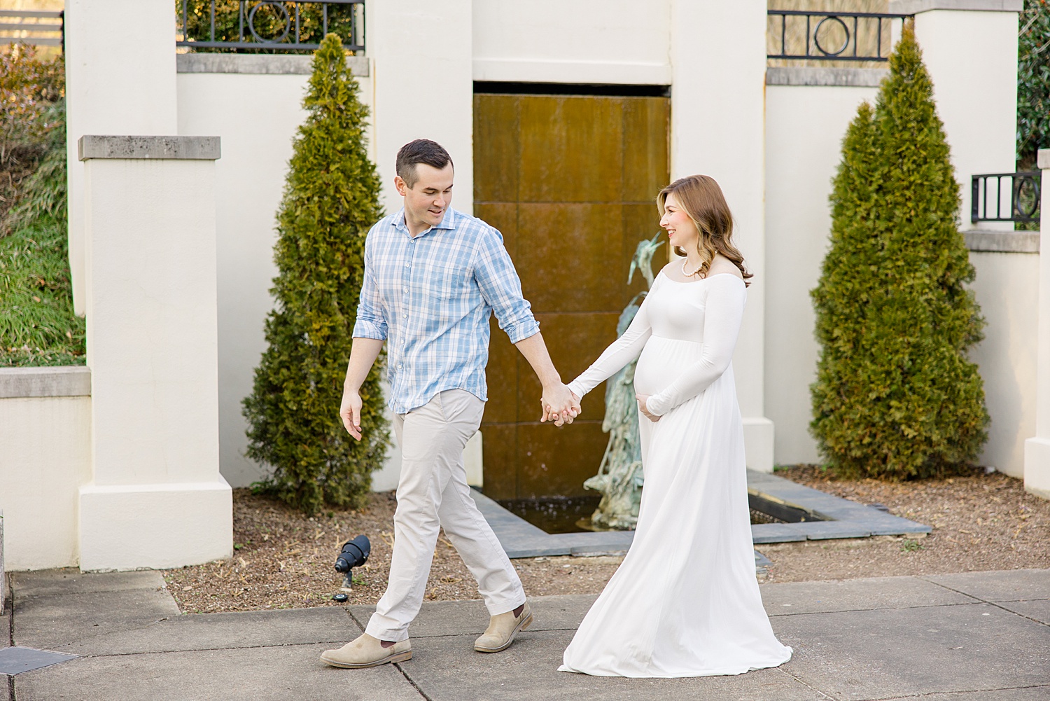 couple walks holding hands during maternity shoot