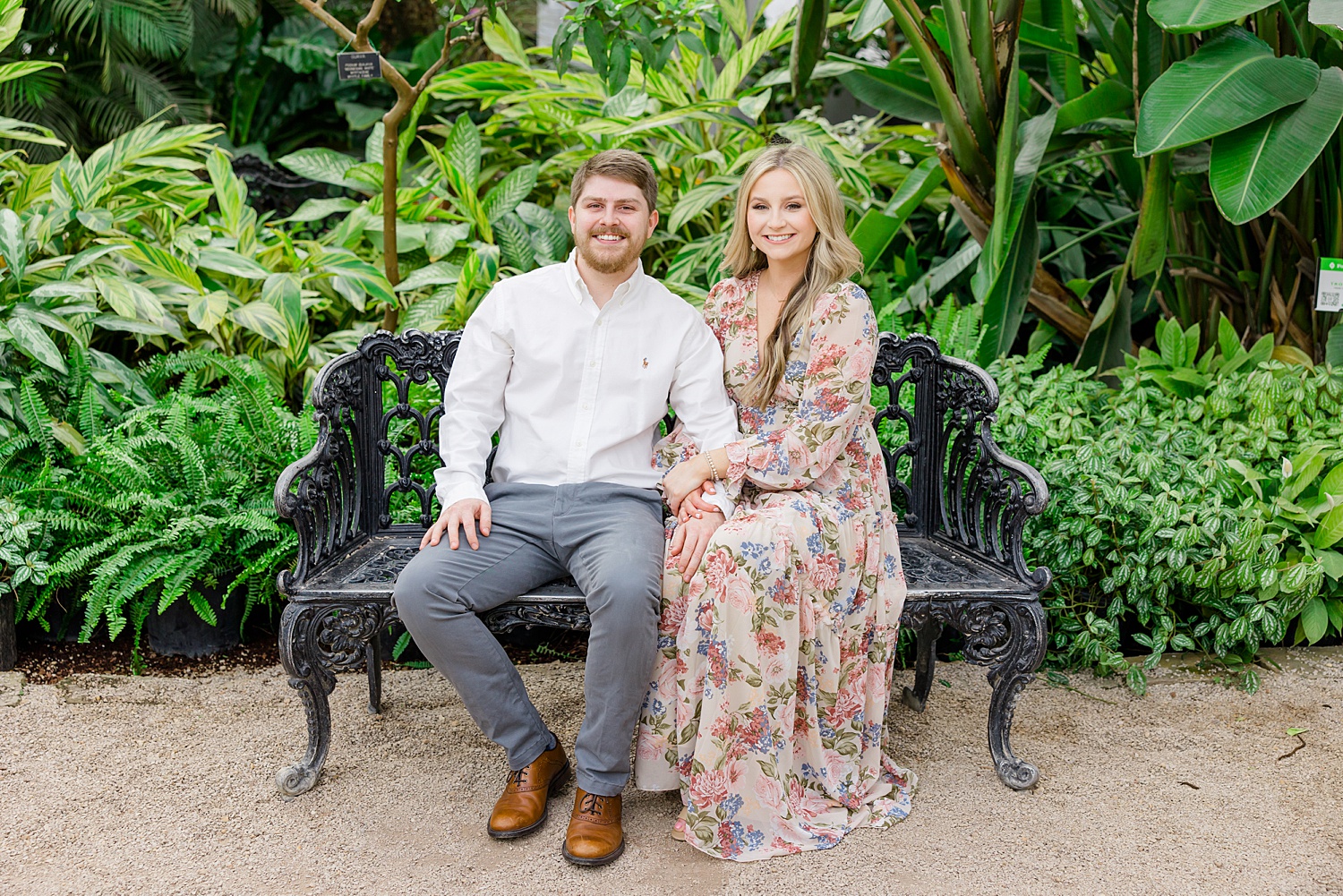 engaged couple sit on garden bench