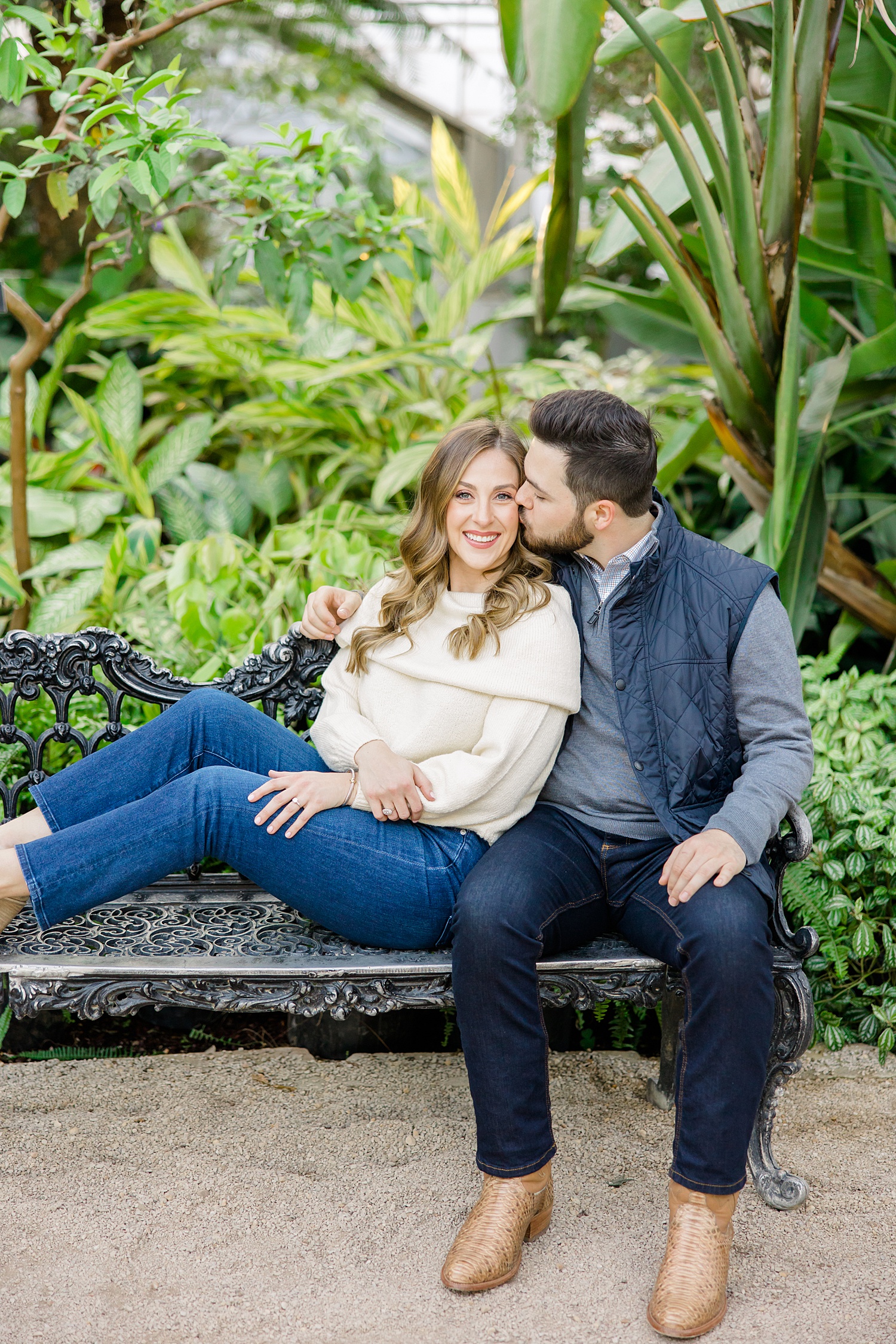 couple lean on each other sitting on bench during engagement session