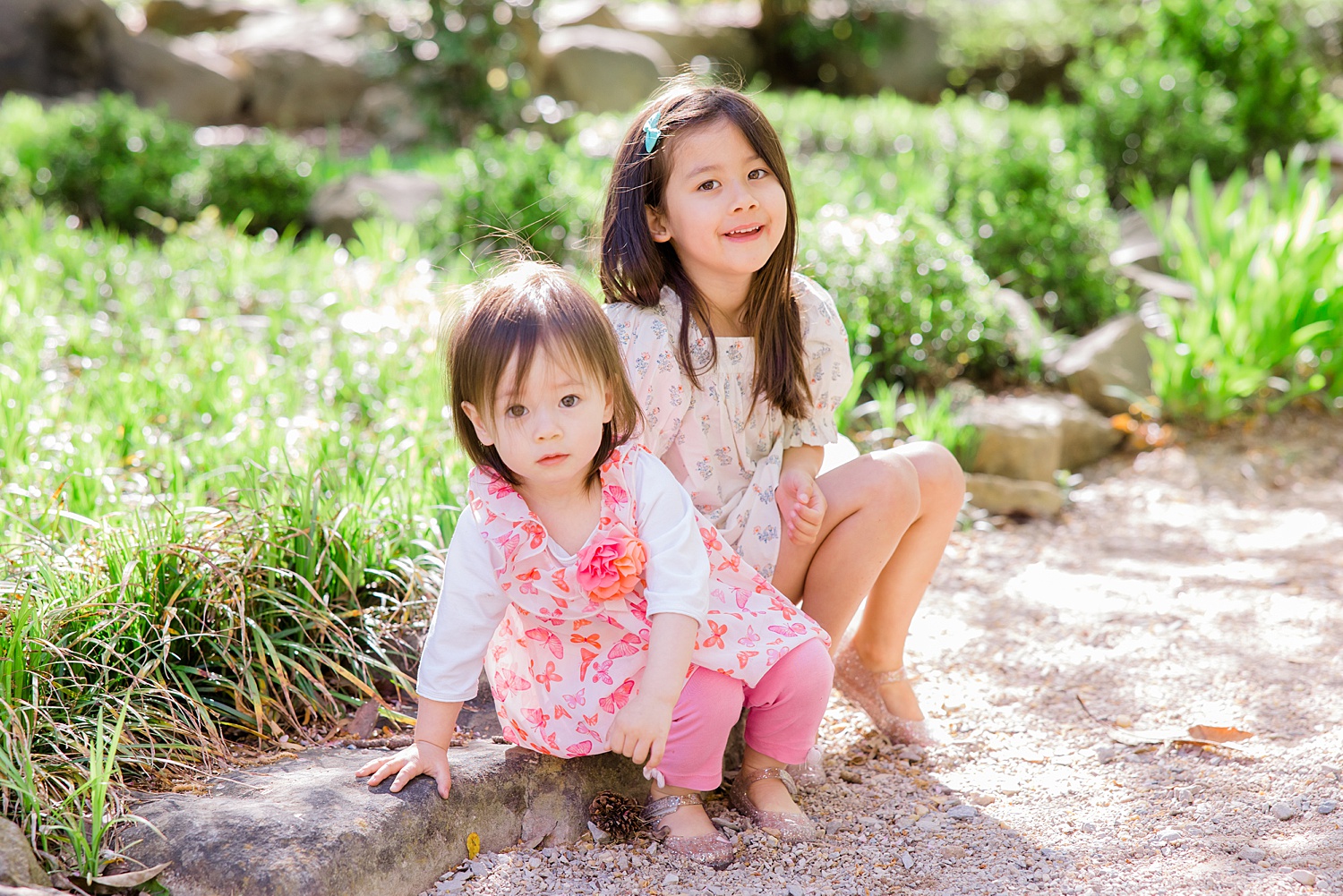 sisters sit together on rock during family minis