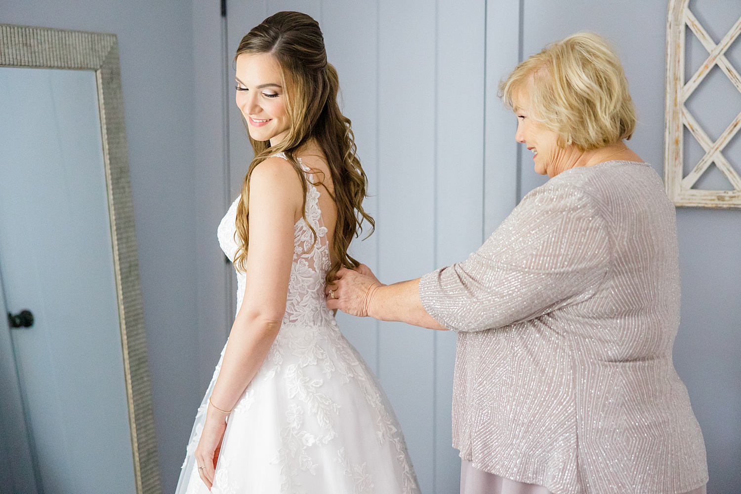 bride getting her dress on with the help of her mom