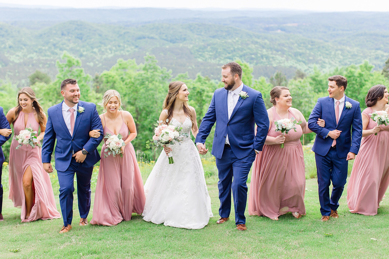 bride and groom hold hands and walk with bridal party behind them 
