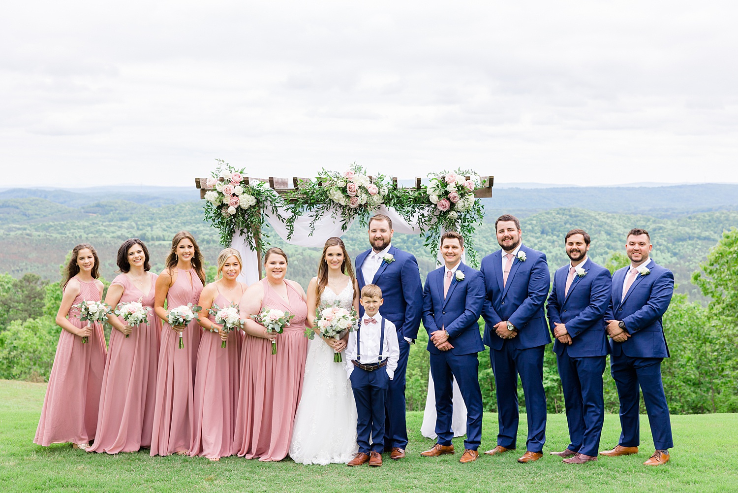 bridal party stands under wedding ceremony arch 