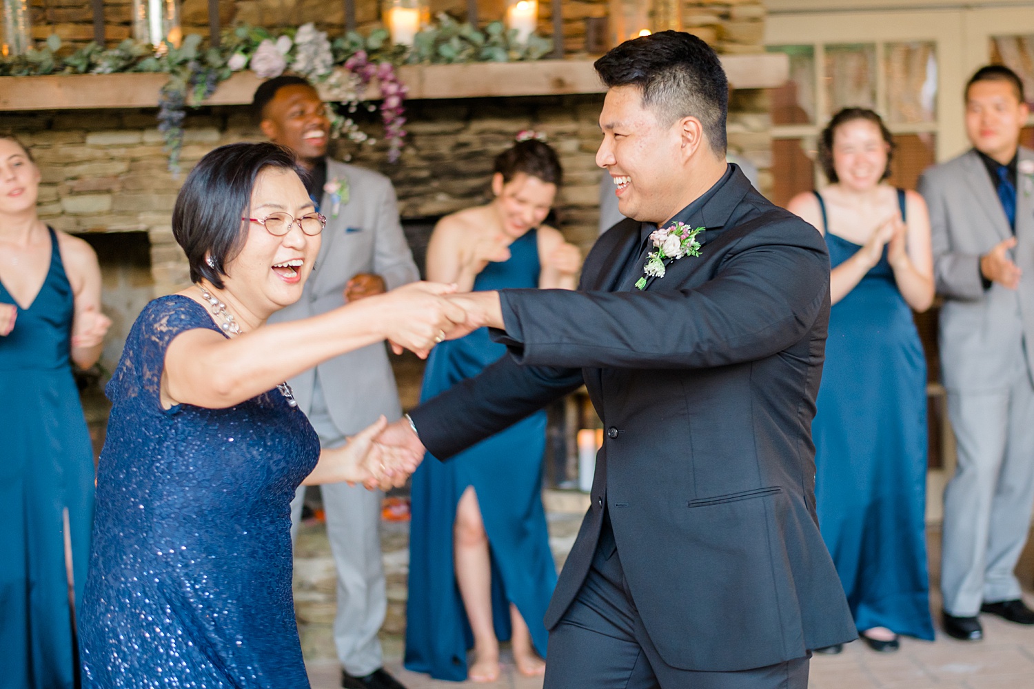 candid photo of groom dancing with his mom as they laugh