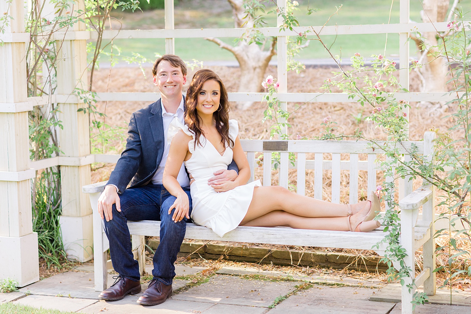 engaged couple sit on bench at Birmingham Botanical Gardens