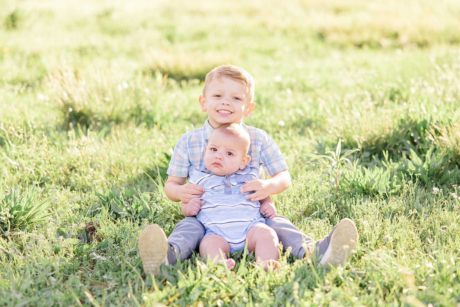 big brother holds his little brother in the grass