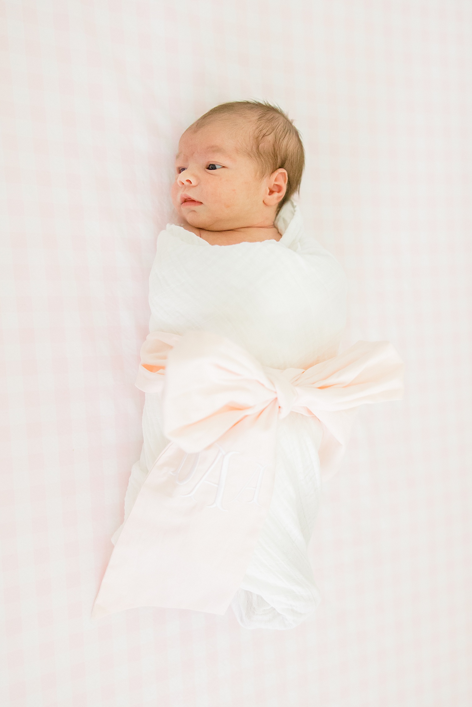 newborn girl wrapped in blanket with pink bow