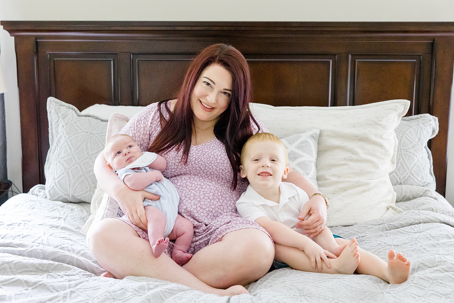 mom cuddles with her two boys on bed during Intimate at-home Newborn + Family Session 