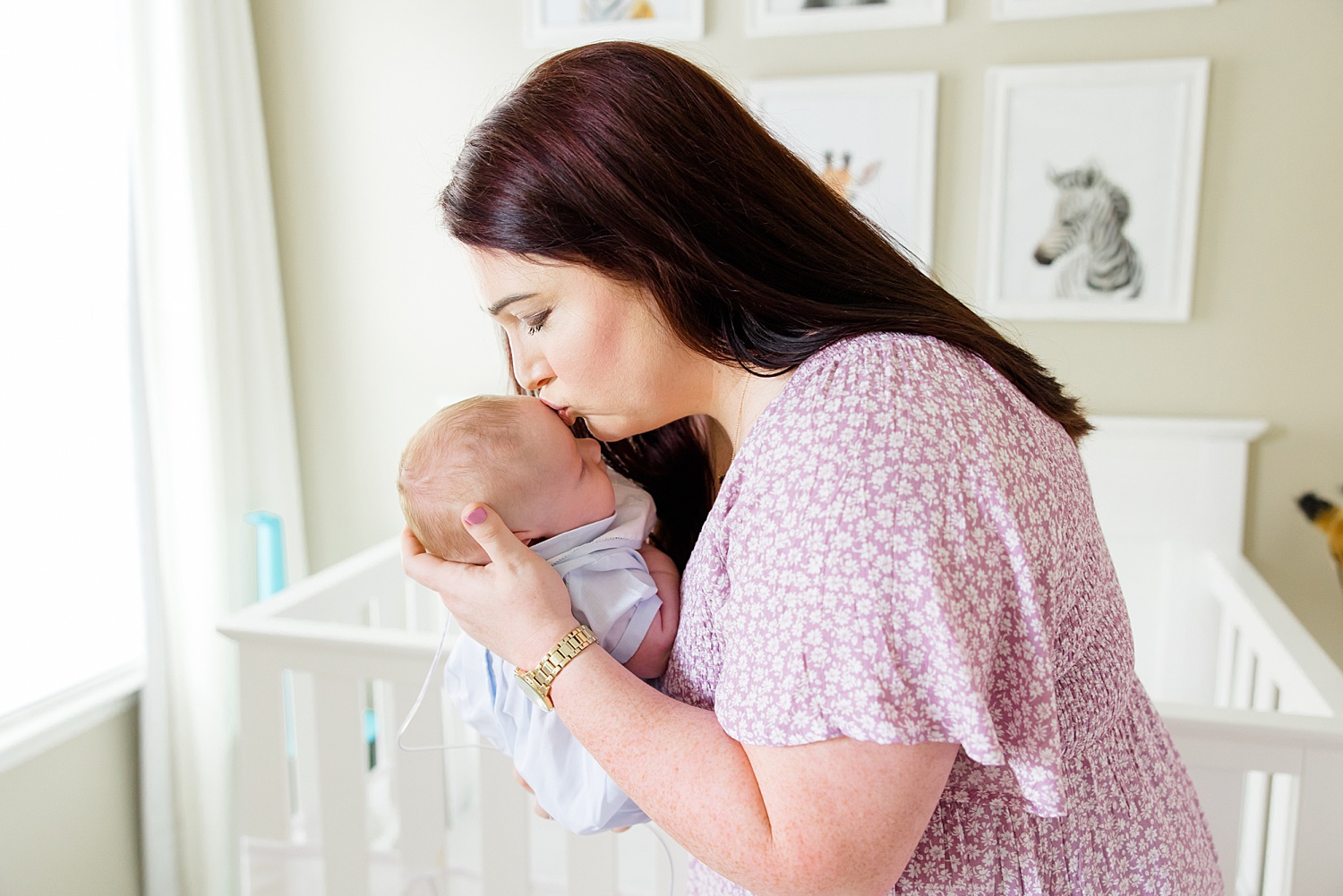 mom kisses newborn son's head in nursery