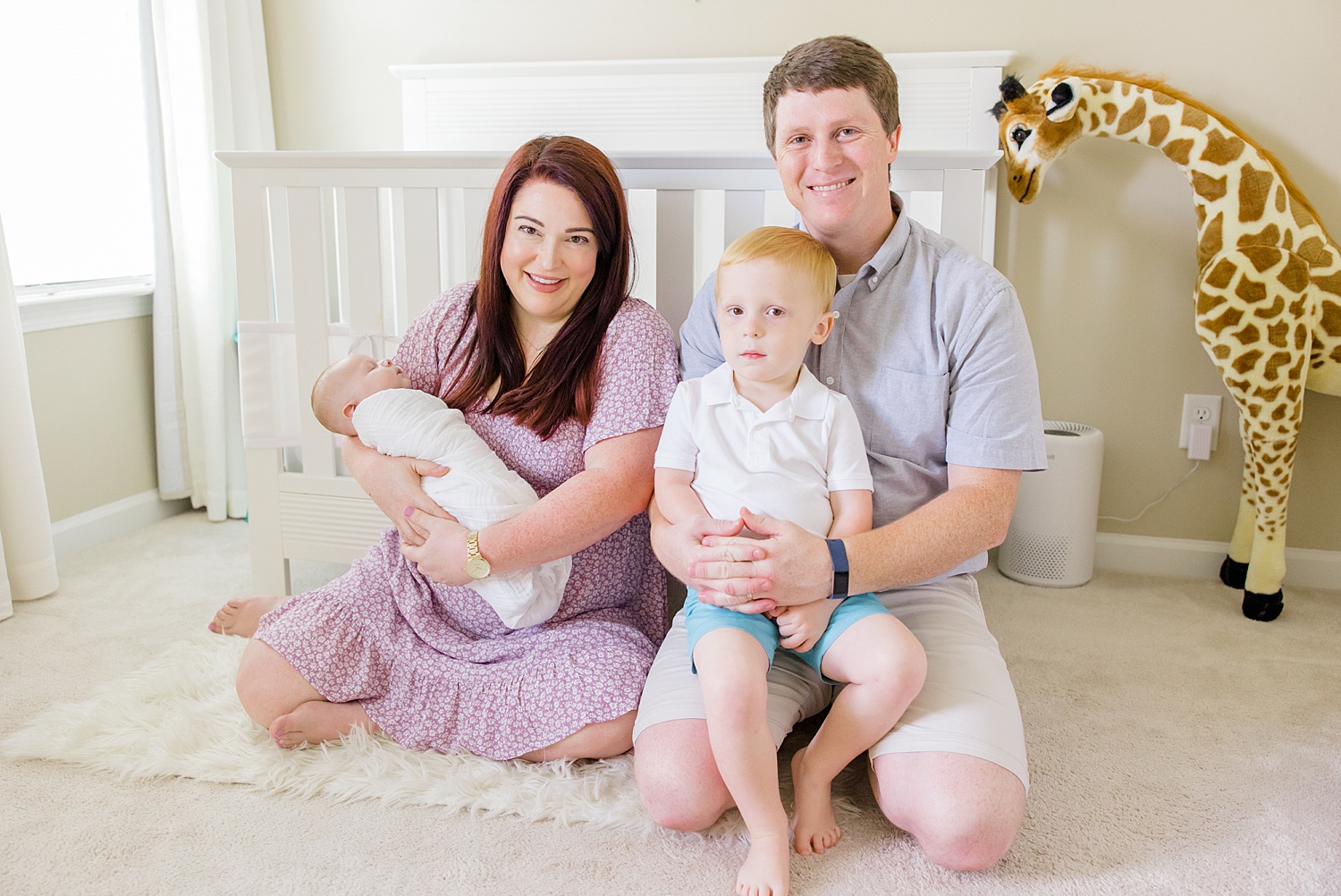 new family of four sits on nursery floor during family portraits by Birmingham family photographer