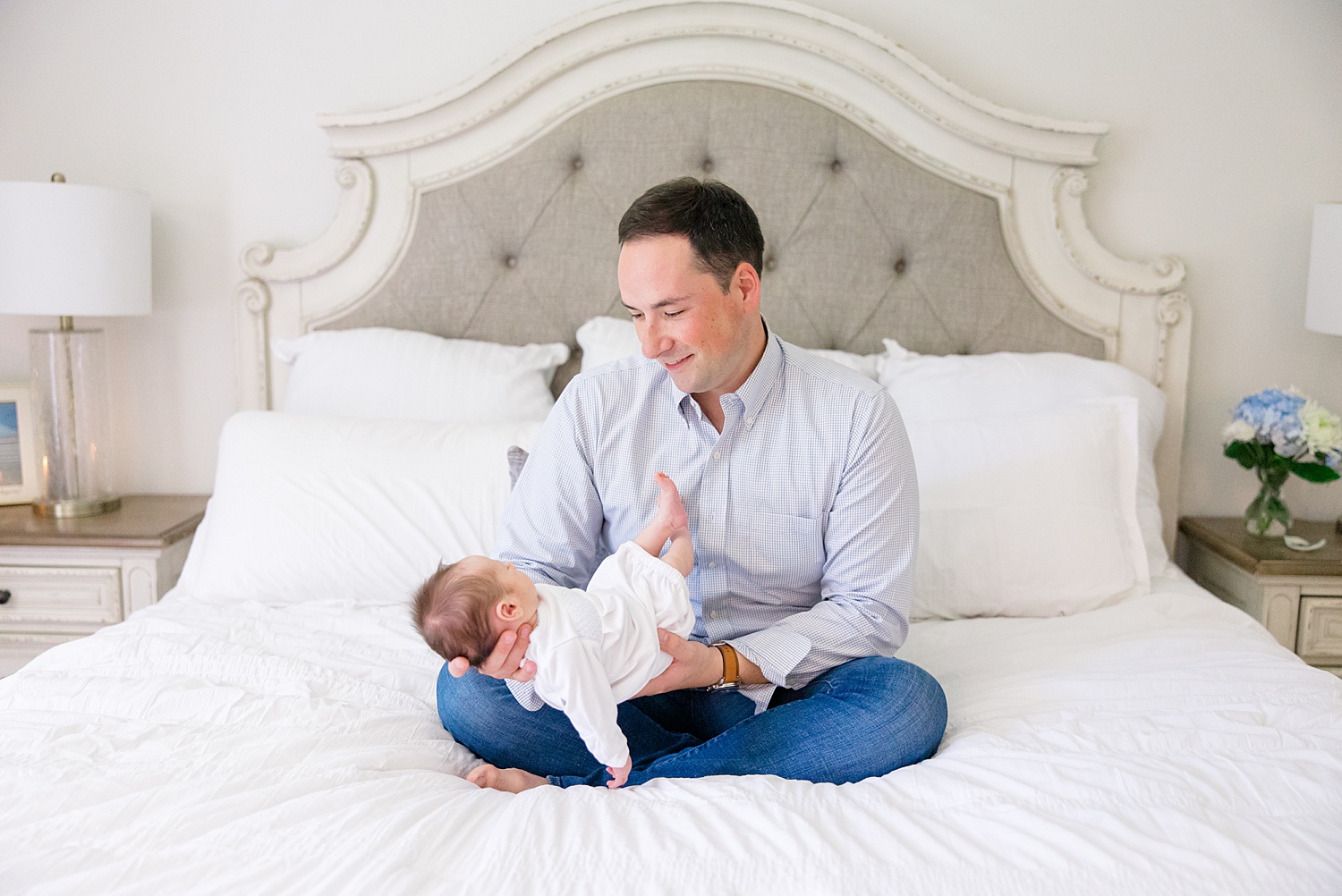 dad and son sit on bed during At-home Newborn + Lifestyle session
