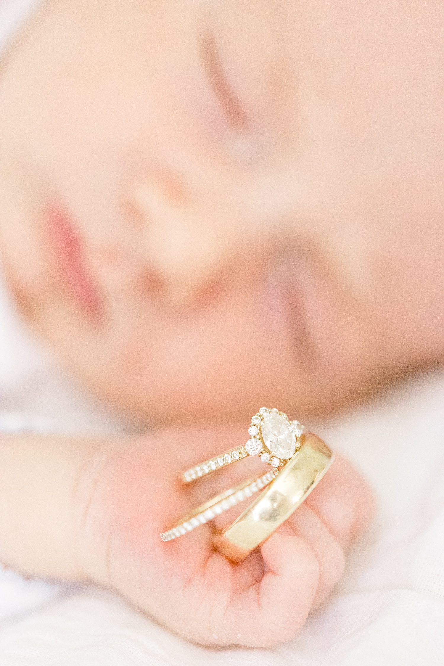 newborn holds parents wedding rings