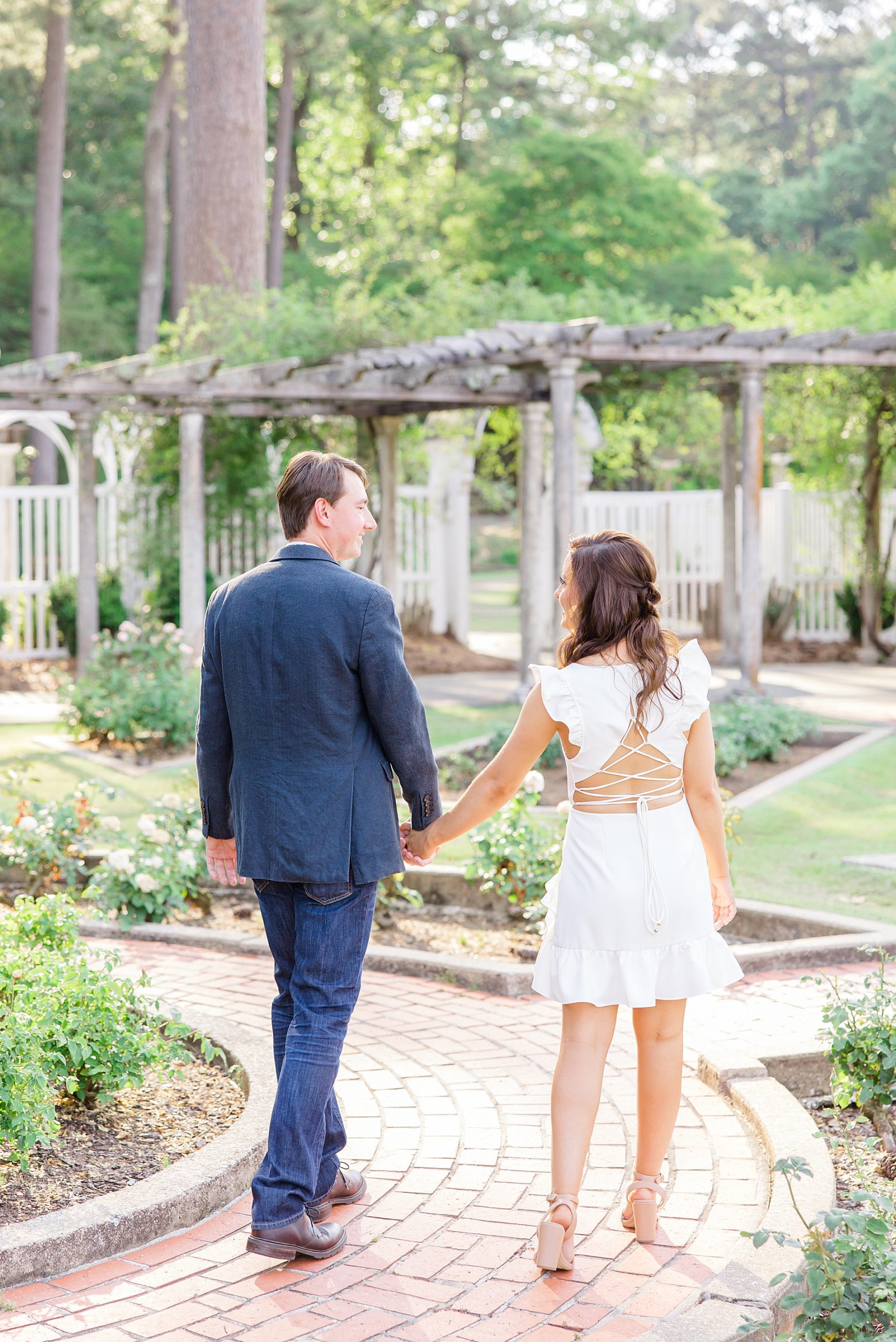 couple holding hands walking through the BIrmingham Botanical Gardens