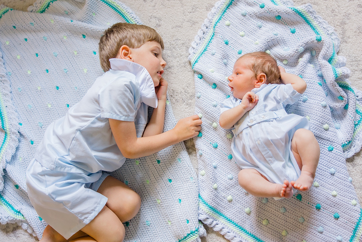 older brother lays with his baby brother on the floor during Newborn and Family Milestone Portraits