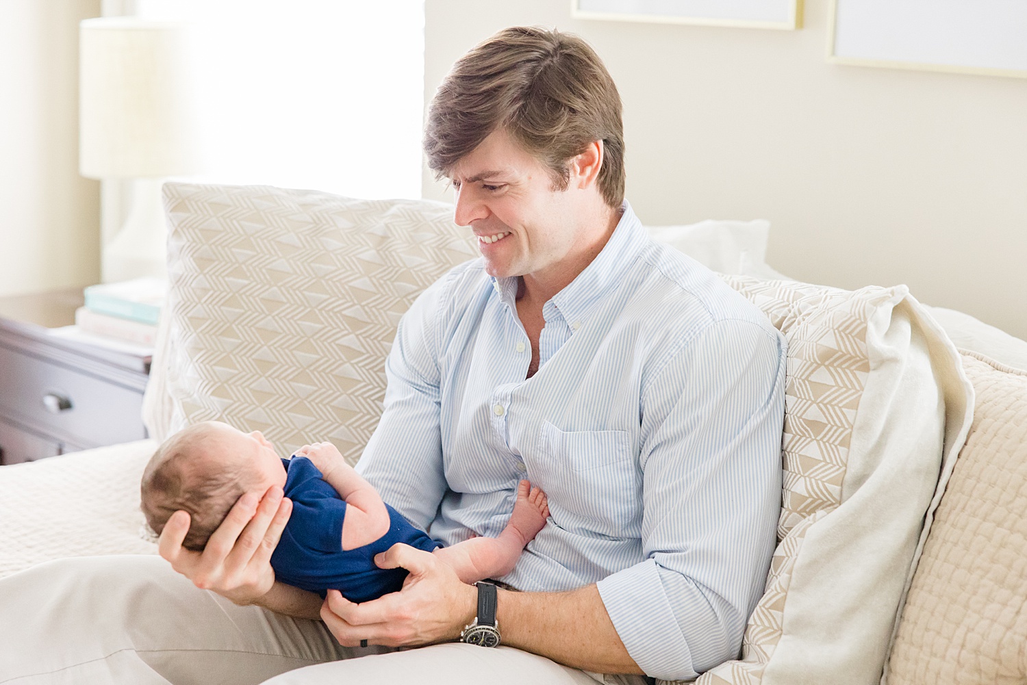 Dad looks down at newborn son during Cozy In-Home Newborn Session