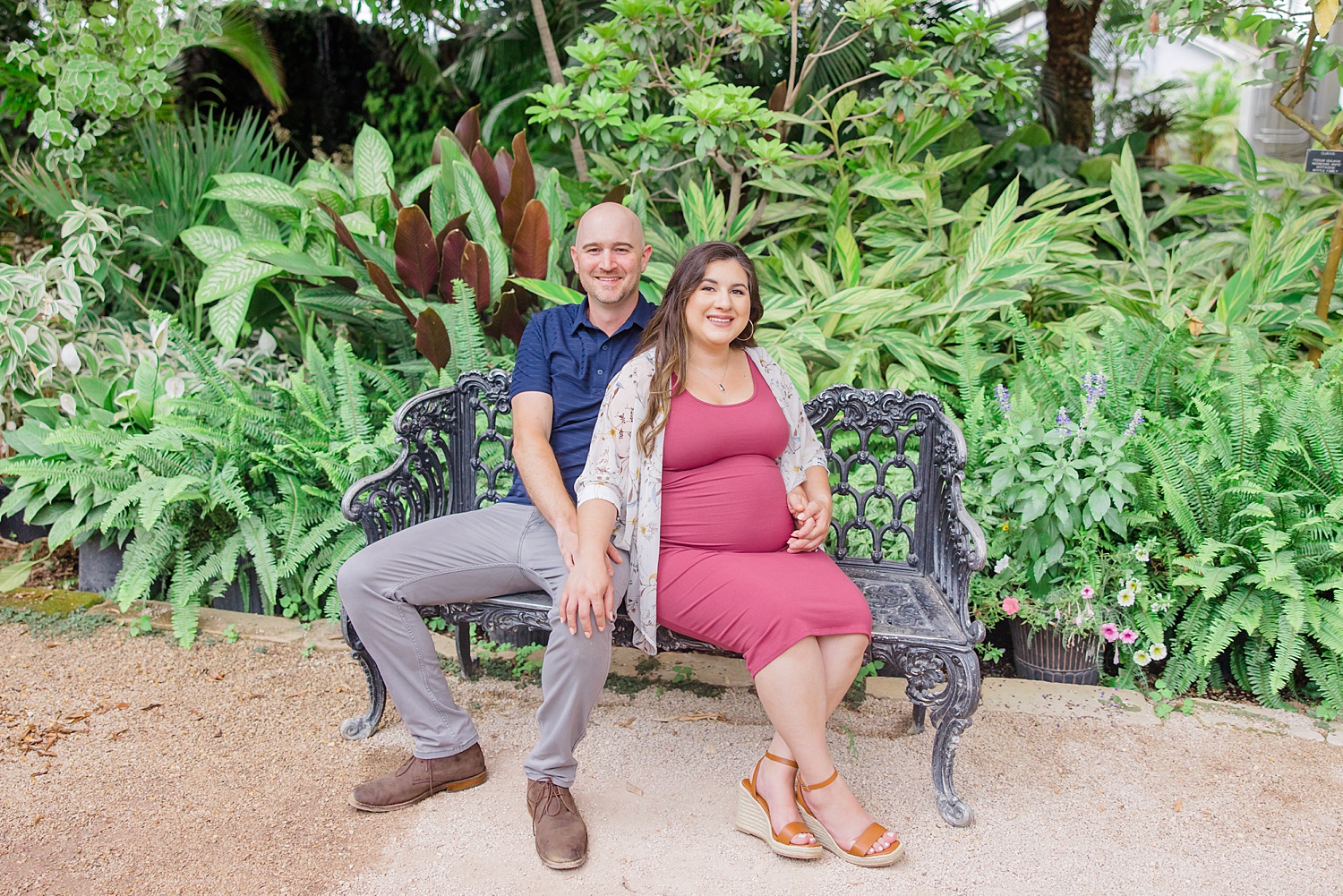 Couple sit on bench at the botanical gardens during Birmingham Engagement + Maternity session