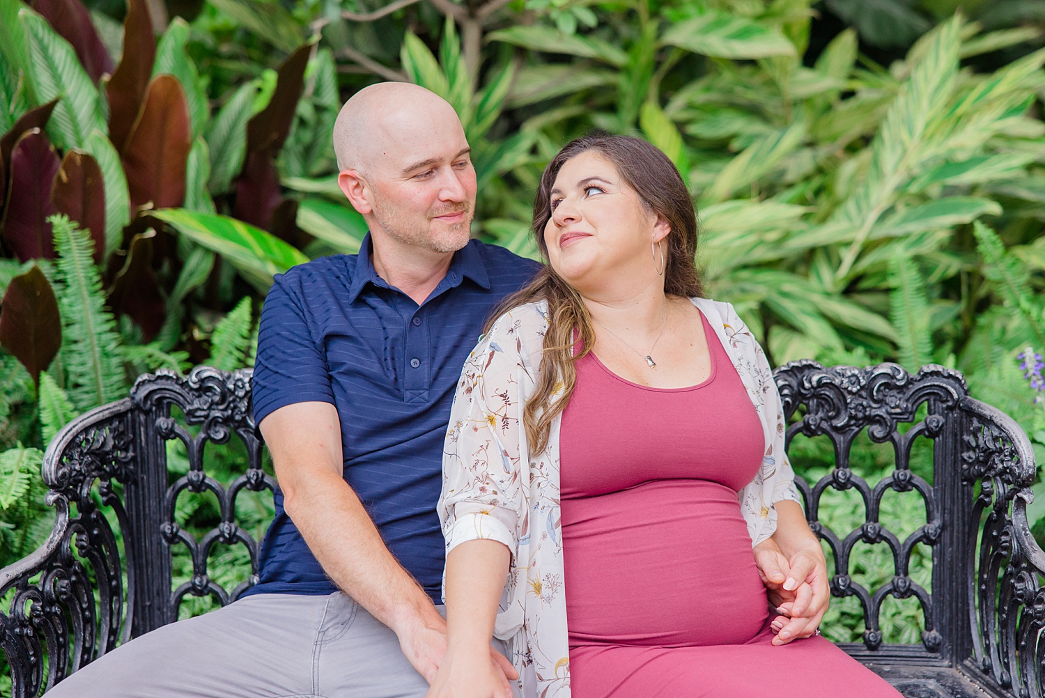 couple sit on bench in the garden during Birmingham Engagement + Maternity session