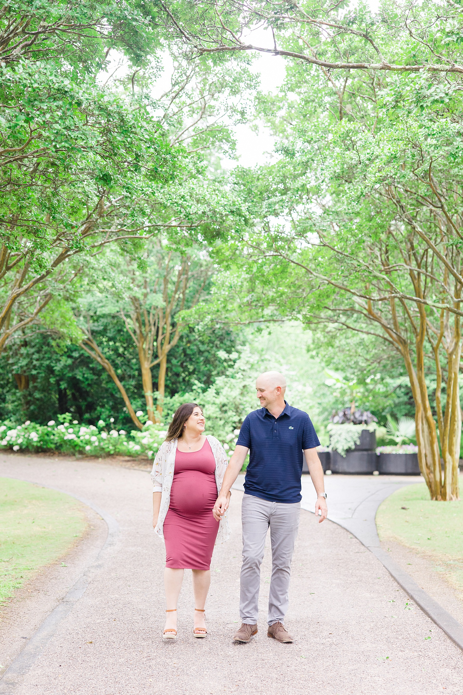 couple walk together holding hands during engagement session at Botanical Gardens 