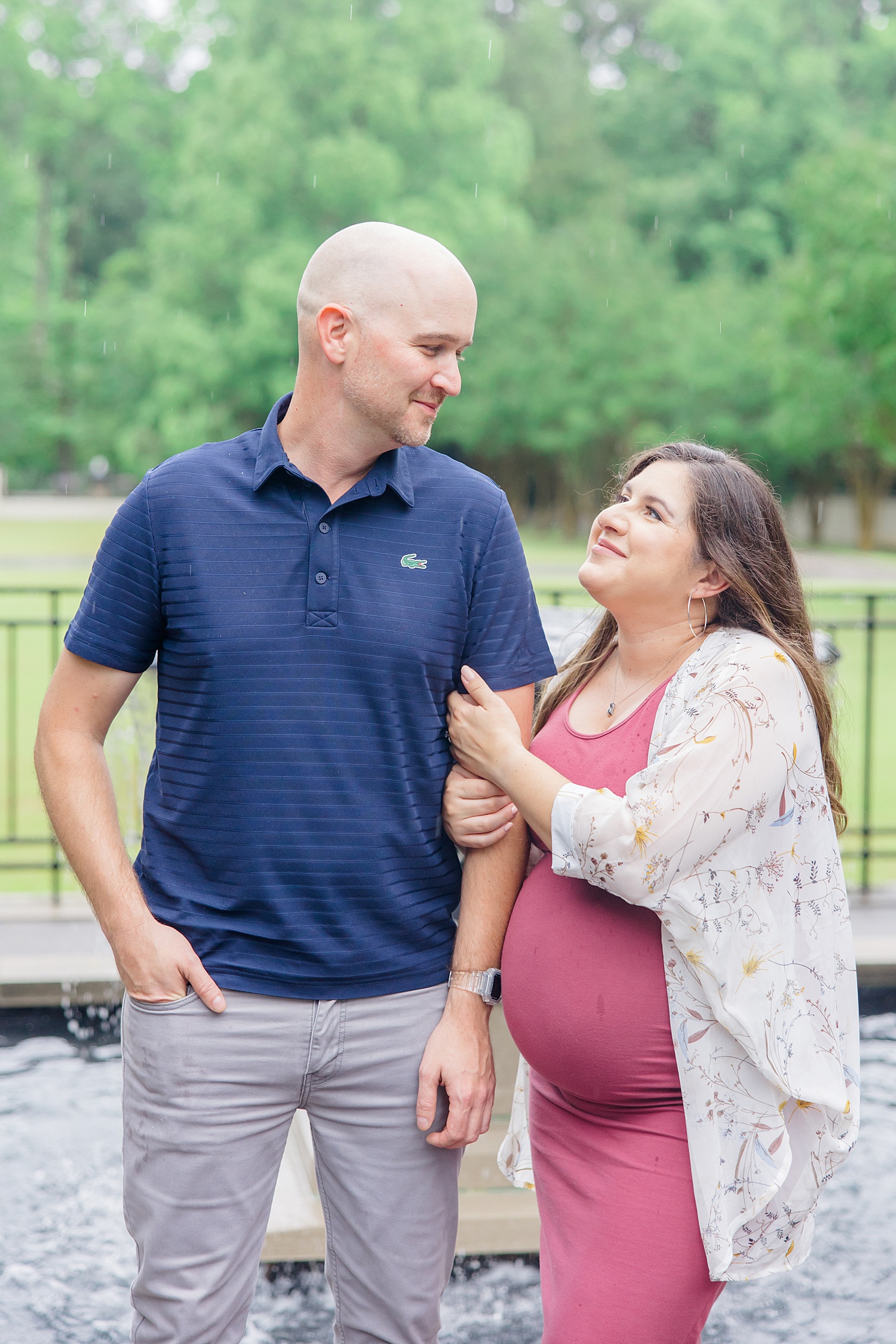 couple look at each other during their Birmingham Engagement + Maternity session