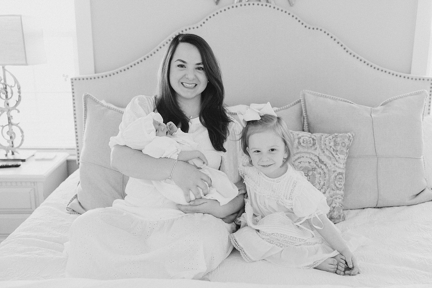 mom holds newborn daughter with her oldest daughter next to her