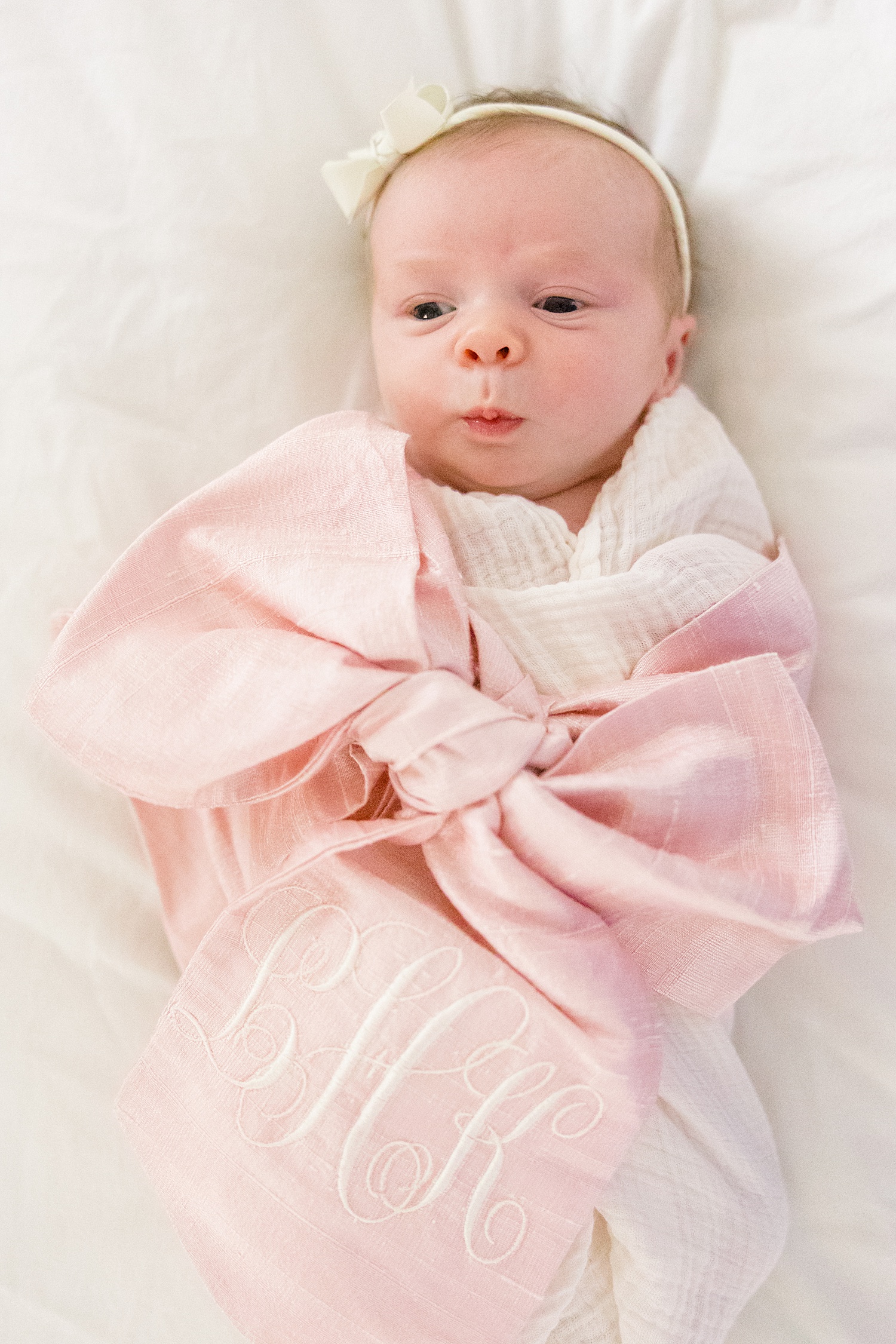 newborn in pink bow blanket