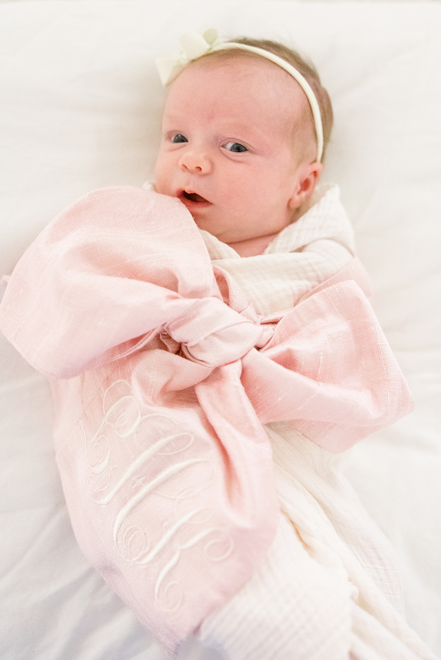 baby girl swaddled in pink bow blanket