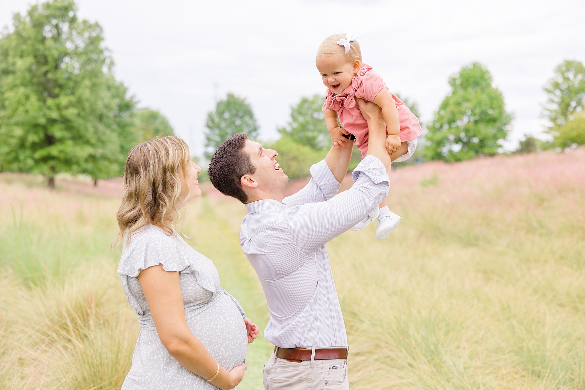 dad holds baby girl up in the air during family portraits
