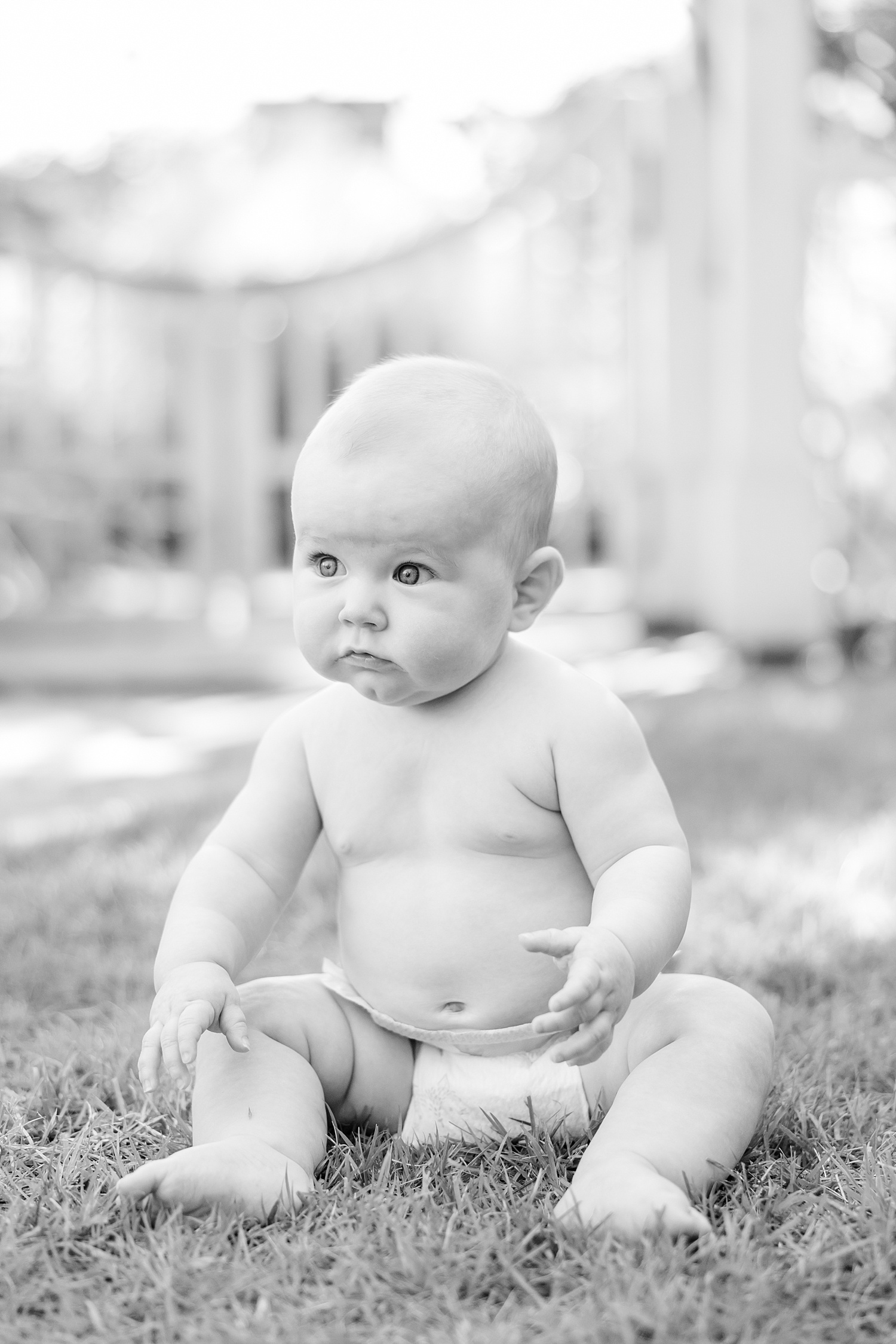 baby sits in the grass with diaper on