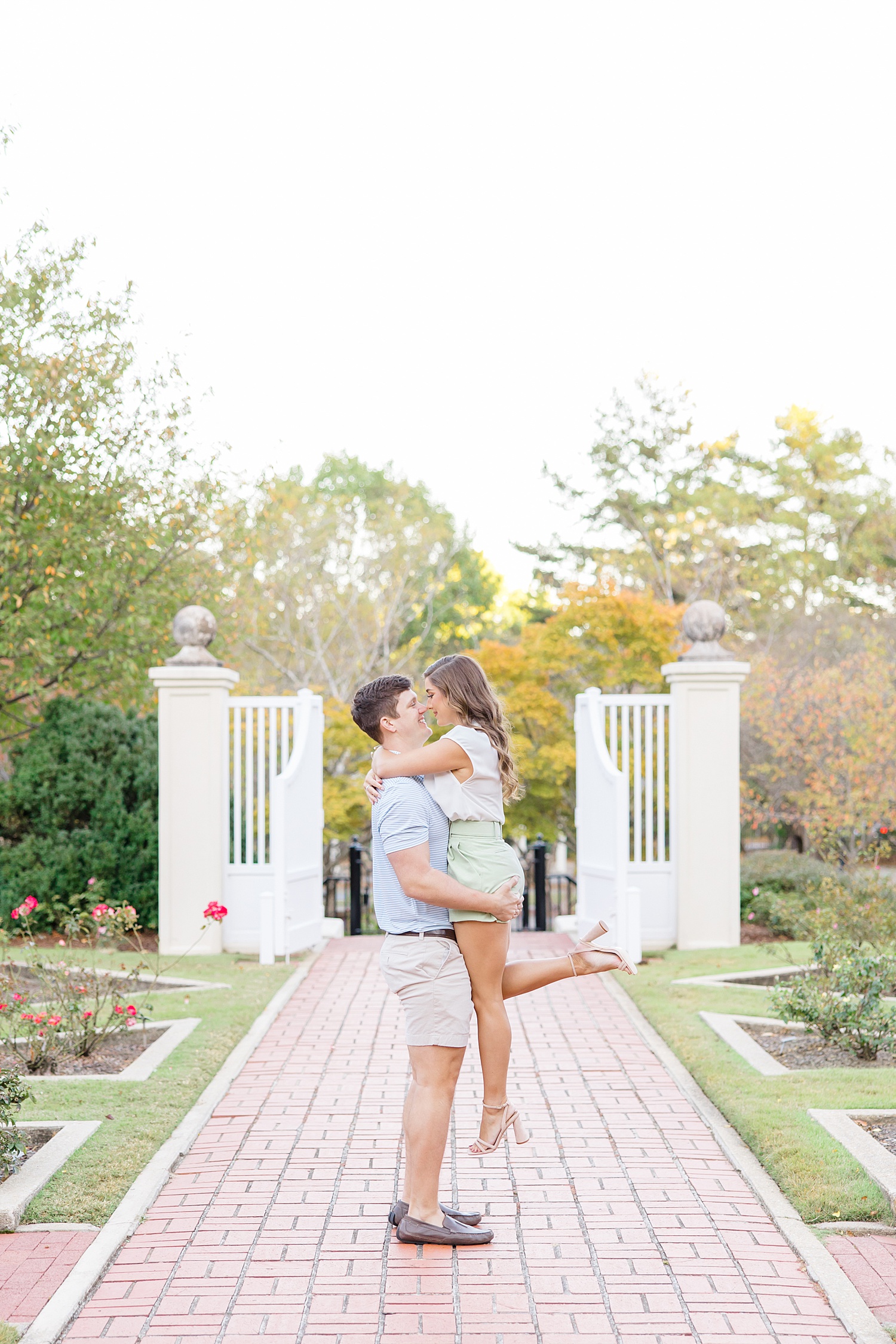 man lifts his fiance up in the garden during engagement 
