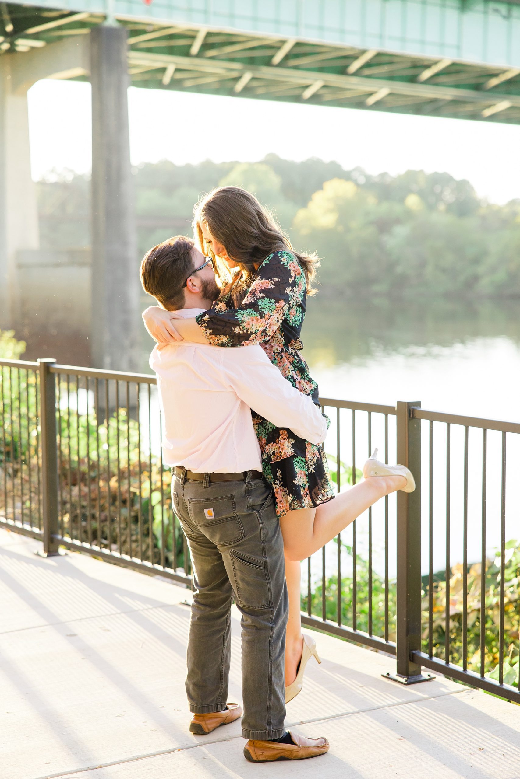 man lifts his fiance up during riverwalk engagement 