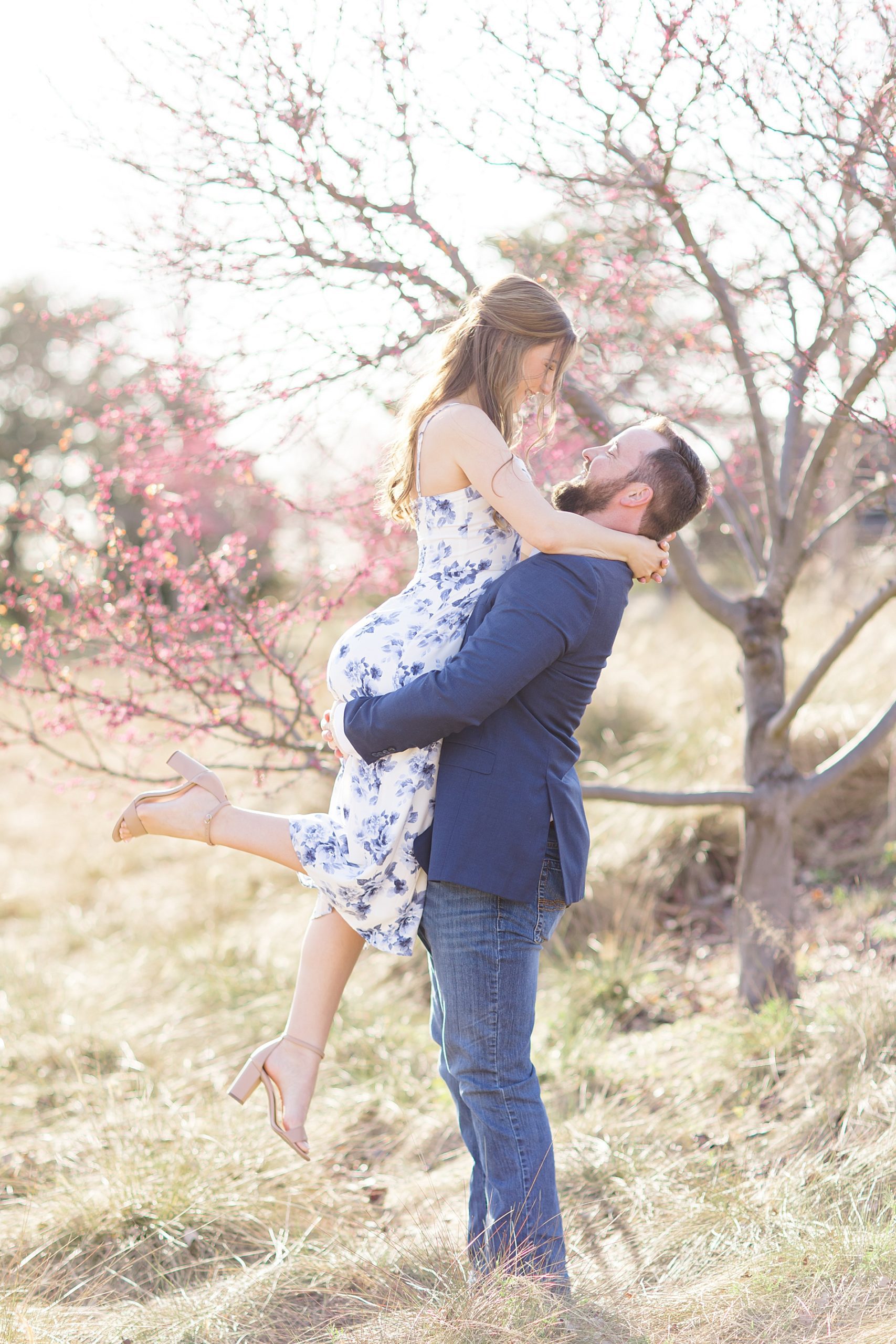 man lifts his fiance up at Railroad park engagement 