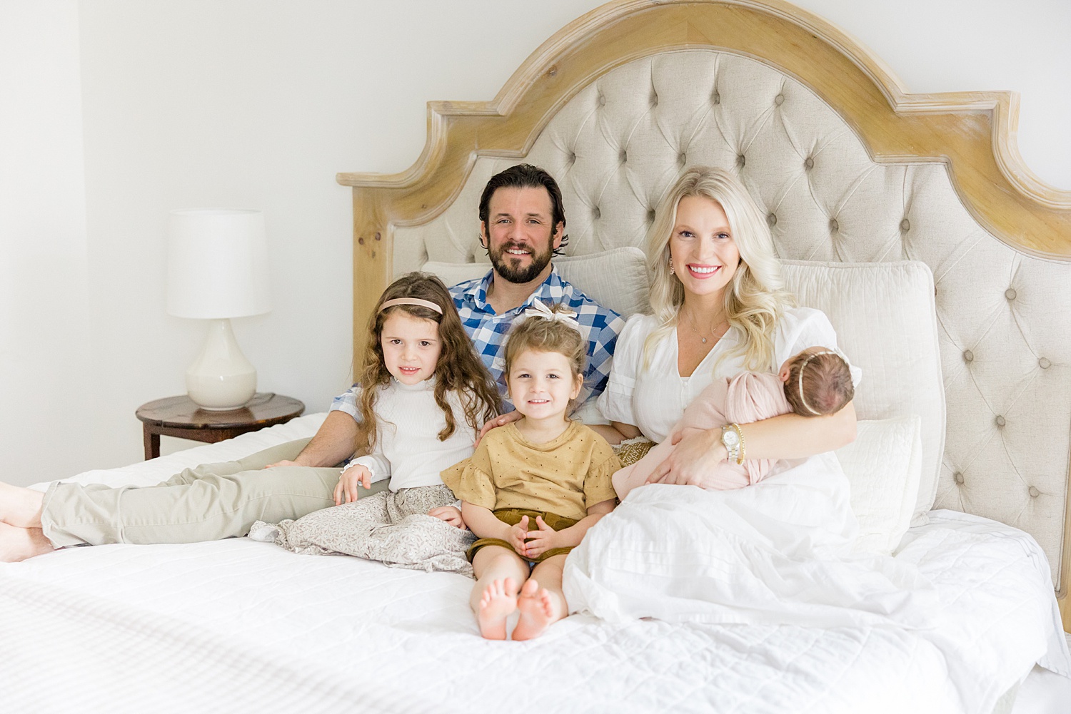 new family of five sit on bed during in-home lifestyle newborn portraits
