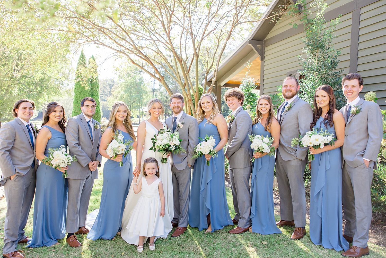 bridesmaids in blue dress and groomsmen in grey suits with bride and groom 