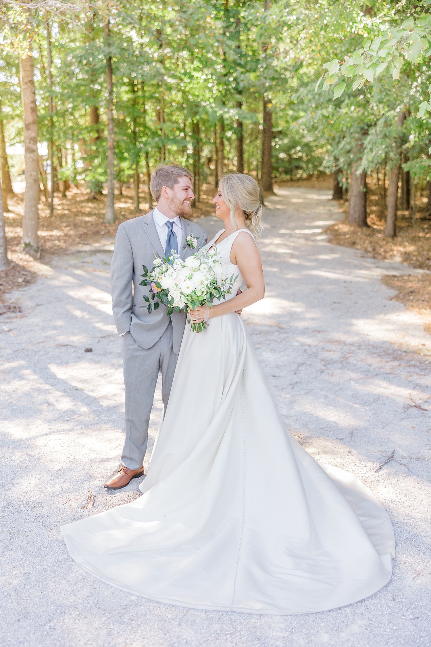 couple look at each other on gravel path at Windwood Equestrian Wedding 
