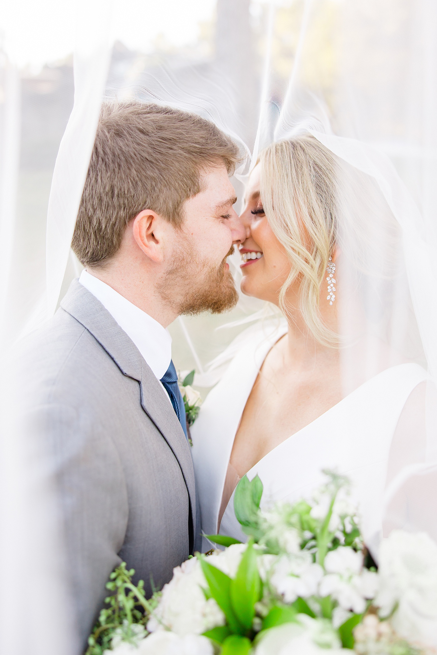 couple kiss under wedding veil